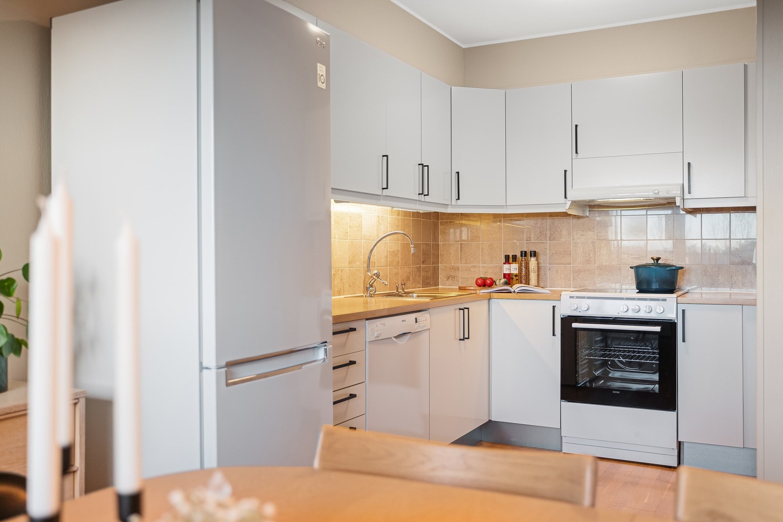 Kjøkkenet er i tidløse hvite farger, med fliser mellom benk og overskap, komfyr. Det er godt med skapplass og benkeplass.
Oppvaskmaskin medfølger leiligheten. Galleribilde