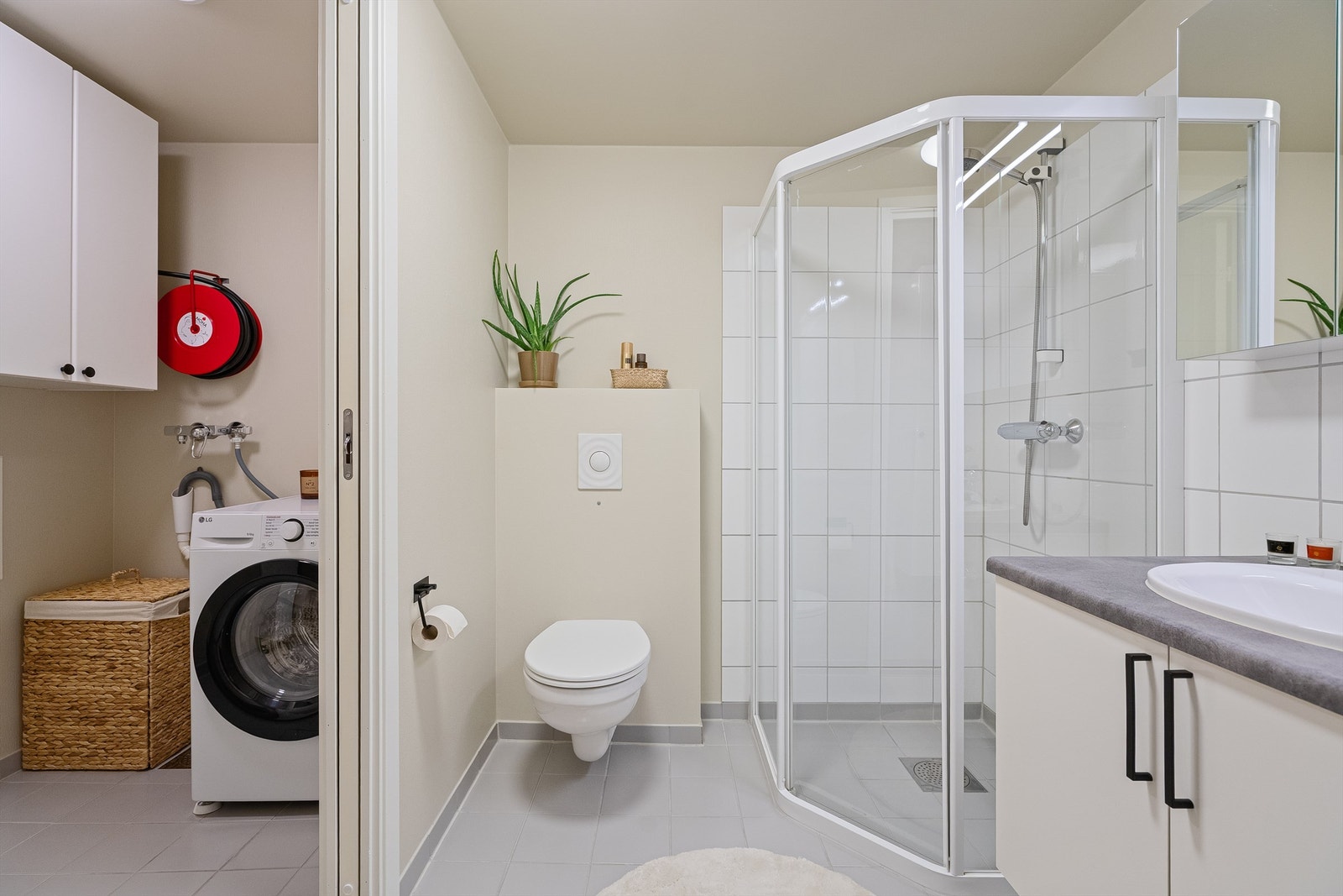 Bad ligger vegg-i-vegg med vaskerom, som kan stenges av med skyvedør. En praktisk og god løsning. Varmekabler i gulv. Opplegg for vaskemaskin og plass til tørketrommel om man skulle ønske det. Høyskap og skap på vegger. Galleribilde