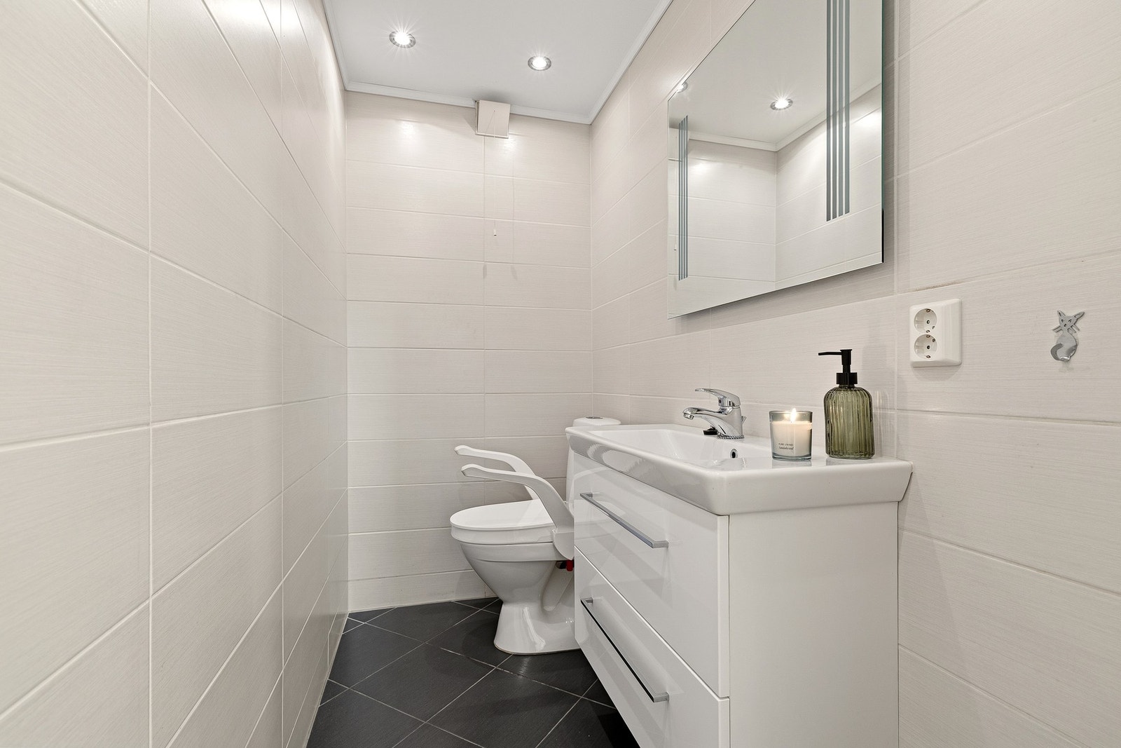 Vegg i vegg med badet ligger en separat wc med fliser på vegger og gulv Galleribilde