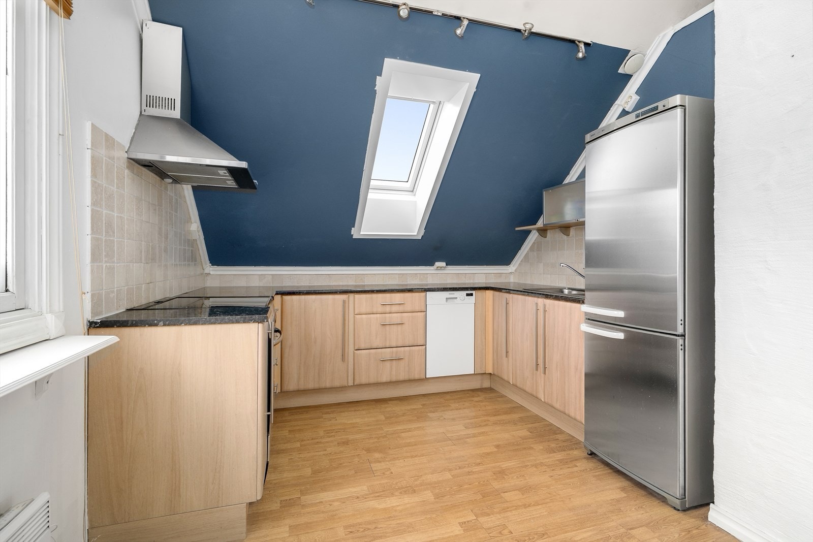 På kjøkkenet er det innredning med slette fronter, og det er benkeplater med gode arbeidsflater. Også her gir takvinduet godt med arbeidslys, og over benken er det fliser som beskytter veggen mot vannsprut og stekefett ved matlaging. Galleribilde