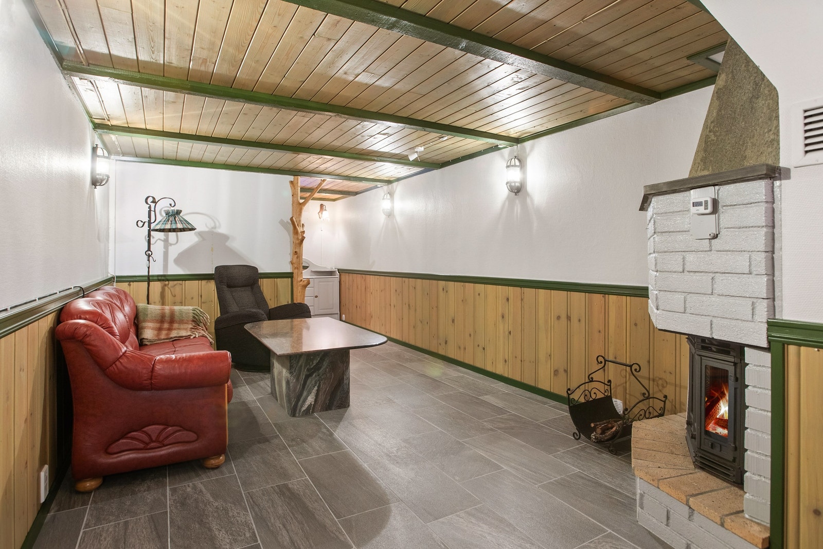 Stor kjellerstue med flislagt gulv og peisovn som gir fra seg godt med varme. Rommet er ikke godkjent for varig opphold Galleribilde