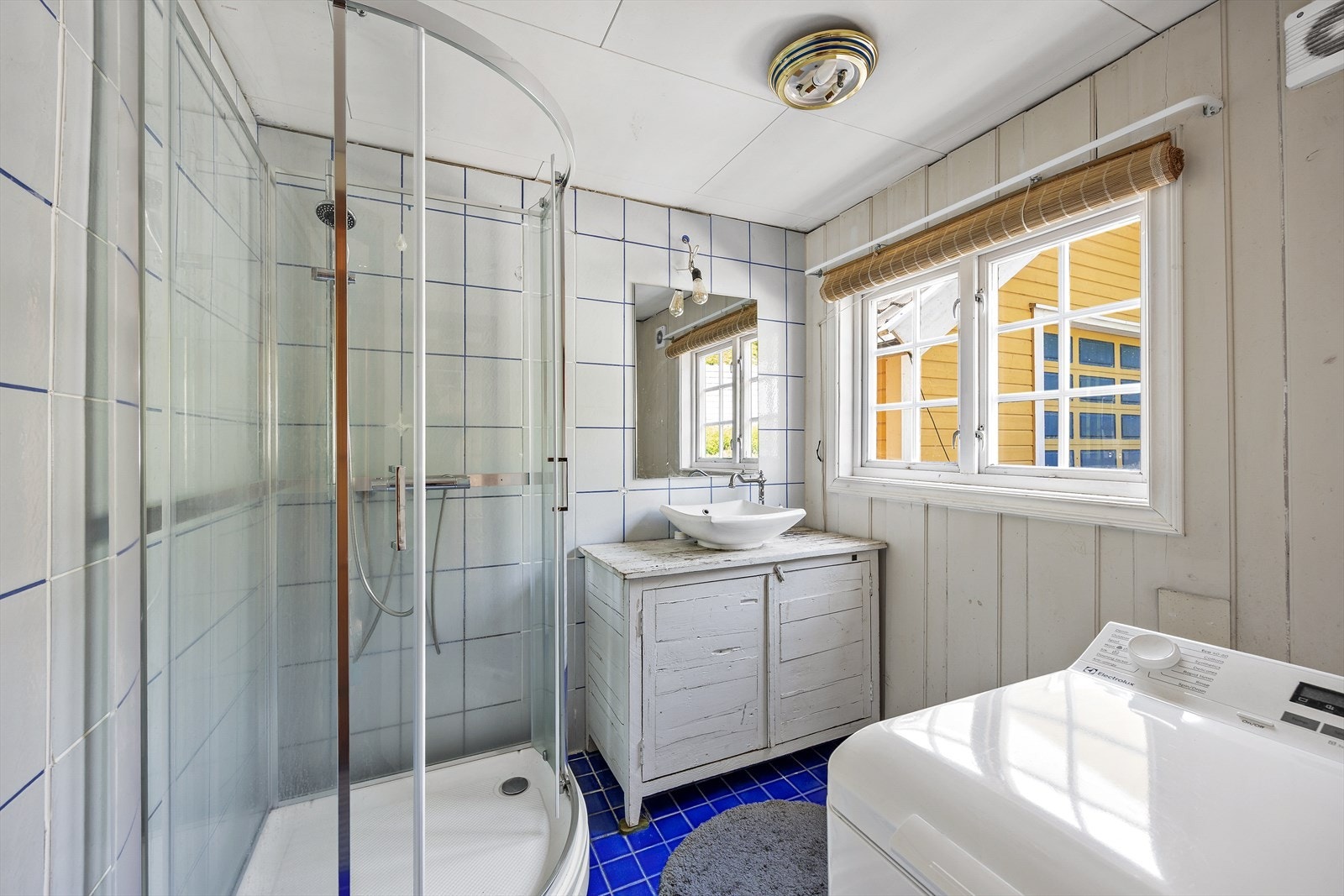 Badet er delvis flislagt og har nyere innredning fra 2024. Innredningen har et rustikt design med toppmontert bolleservant over skapmøblement og speil i overkant. Galleribilde