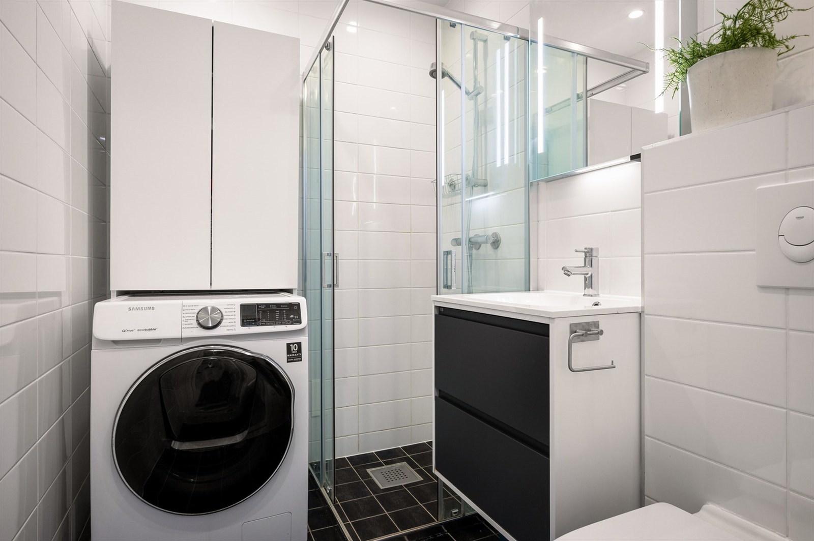 Lyst, flislagt bad fra 2014 med varmekabler, dusjnisje med glassdører, vegghengt toalett og mekanisk avtrekk. Galleribilde