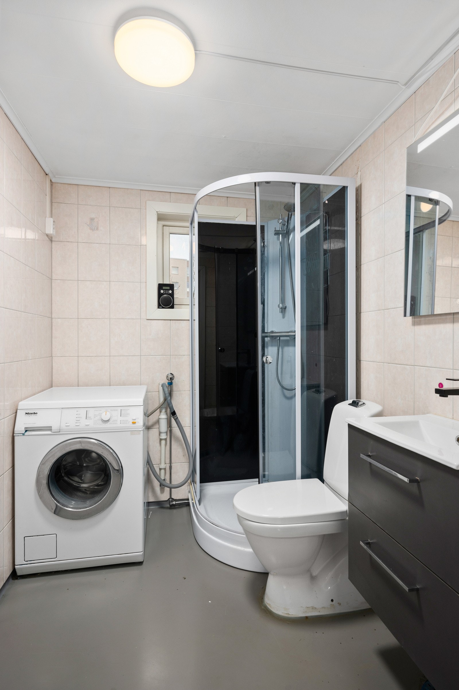 Baderommet er innredet med dusjkabinett, servant med skap, toalett og opplegg for vaskemaskin. Galleribilde