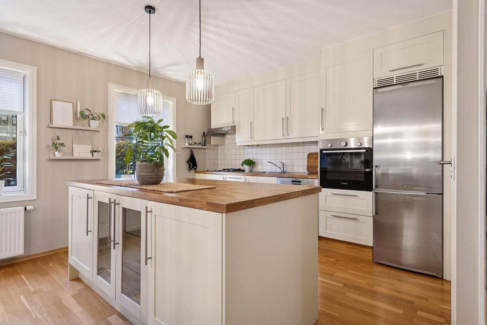 Moderne kjøkken fra Norema med laminert benkeplate, flislagt over benk og kjøkkenøy. God plass til matlaging og integrerte hvitevarer for en praktisk hverdag. Galleribilde