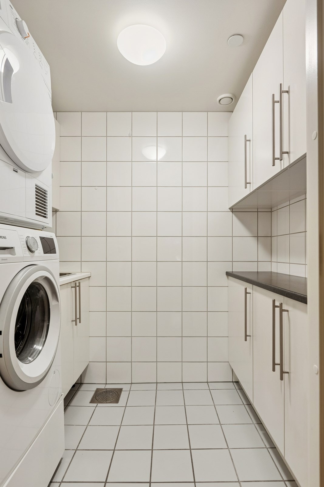 Eget flislagt vaskerom med muligheter for oppbevaring i installert innredning. Galleribilde