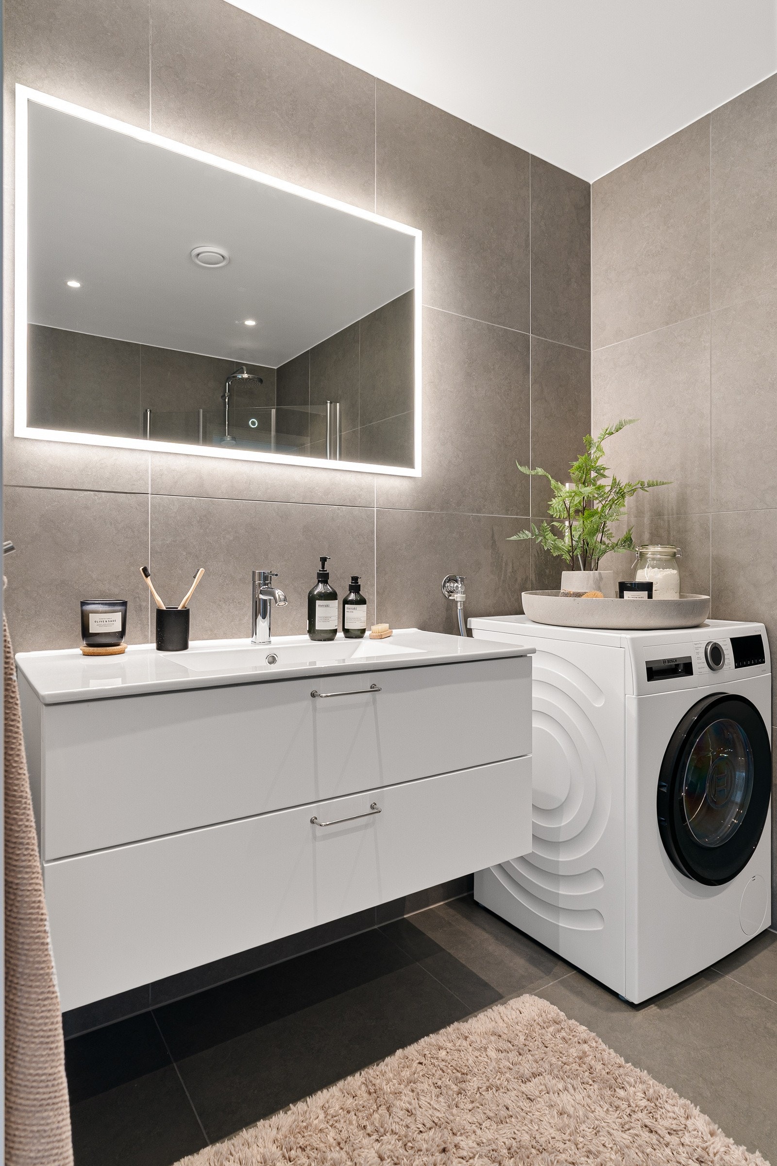 Badet er utstyrt med en fin baderomsinnredning med servant, speil med bakbelysning, opplegg for vaskemaskin samt vegghengt wc. Galleribilde