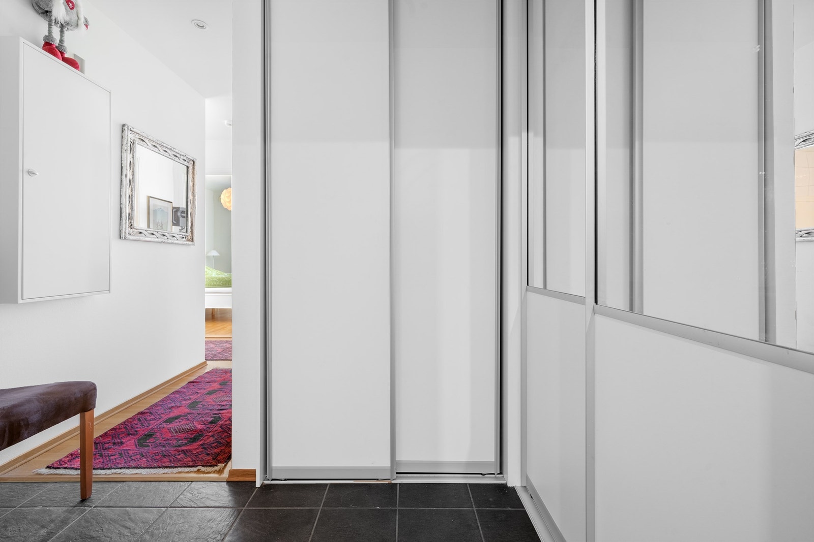 Praktisk flislagt entre med skyvedørsgarderober Galleribilde