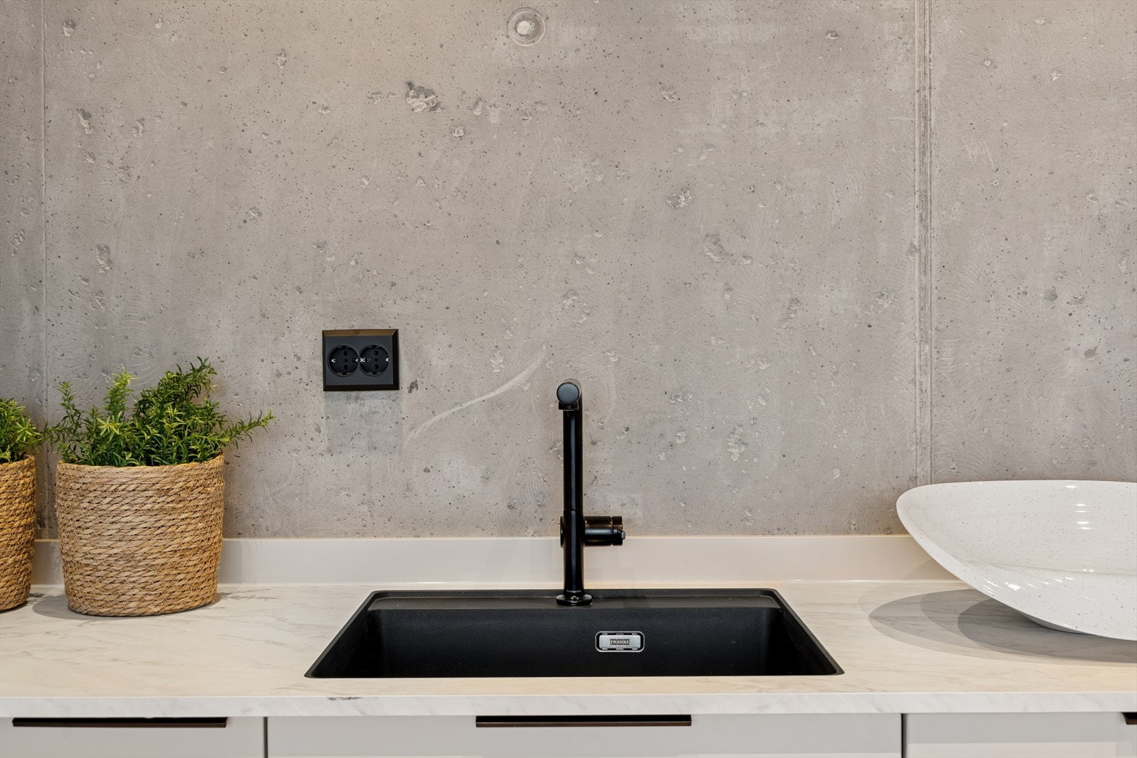 Sort oppvaskkum, armatur, stekeovn/kaffemaskin og sorte stikk/håndtak, skaper en fin kontrast mot det øvrige lyse. Galleribilde