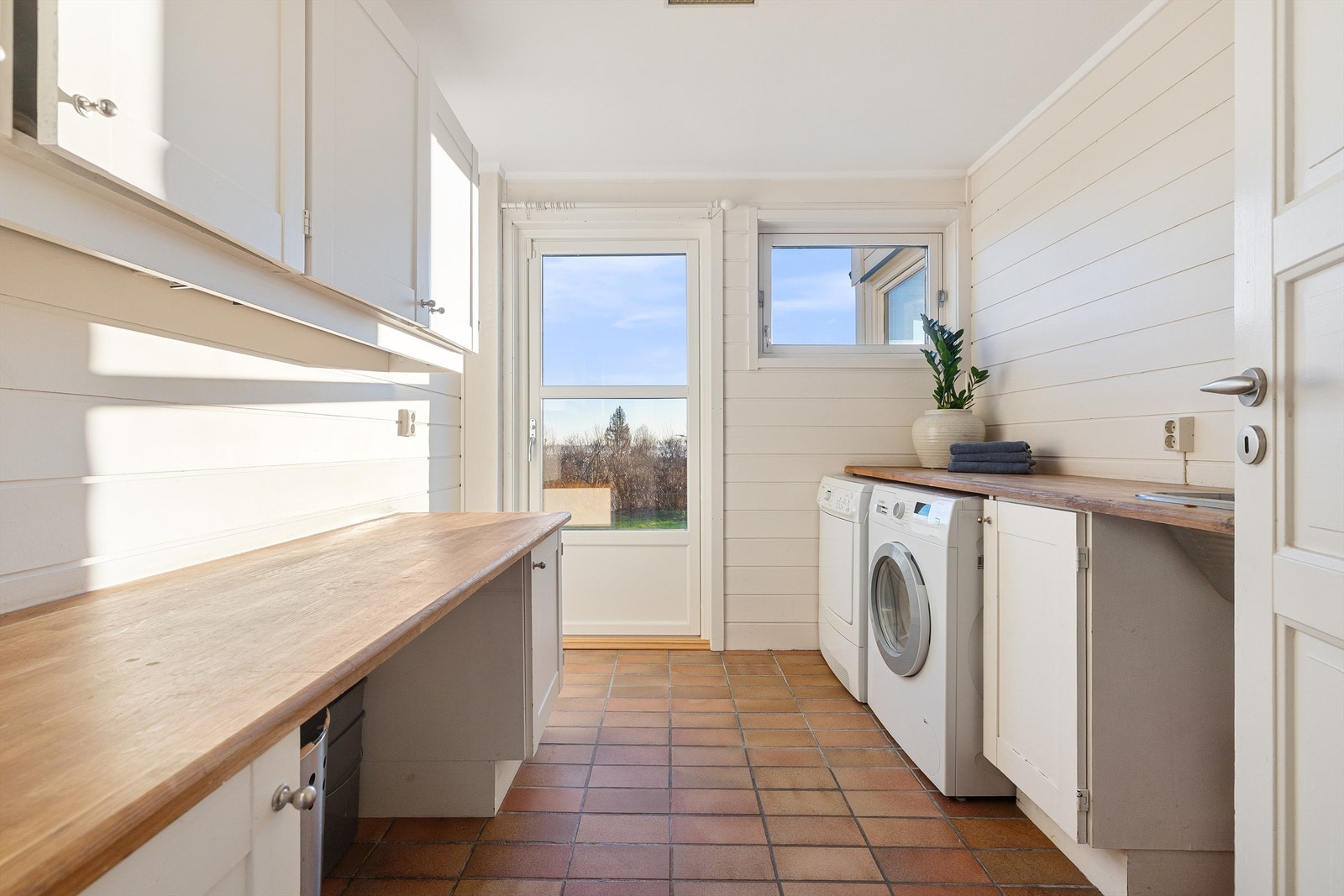 Praktisk vaskerom med direkte utgang til felles hage. Benkeskap med benkeplater i tre, overskap og utslagsvask med ett-greps armatur. Rommet har avtrekksventil i himlingen. Vaskemaskin og tørketrommel medfølger. Galleribilde