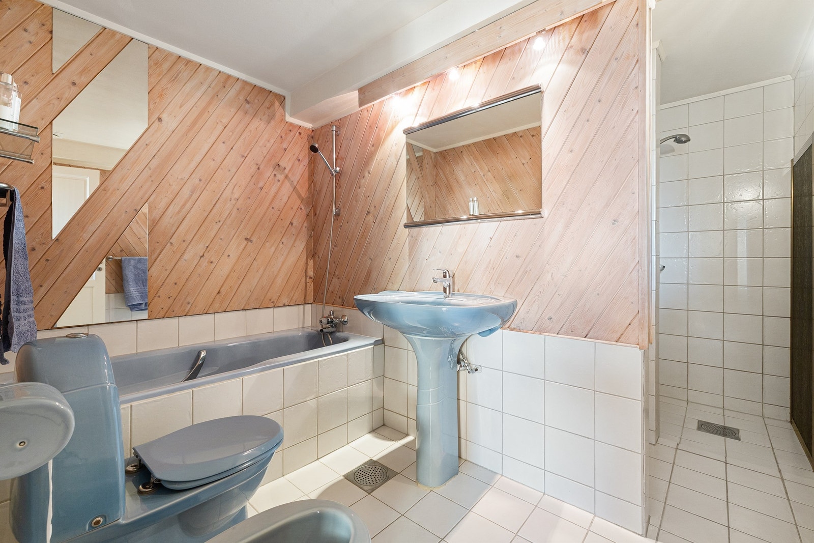 Funksjonelt innredet baderom fra byggeår med servant, speil med belysning, gulvstående toalett og bidé, innbygd badekar og dusjhjørne. Rommet har avtrekksventil i himlingen. Galleribilde