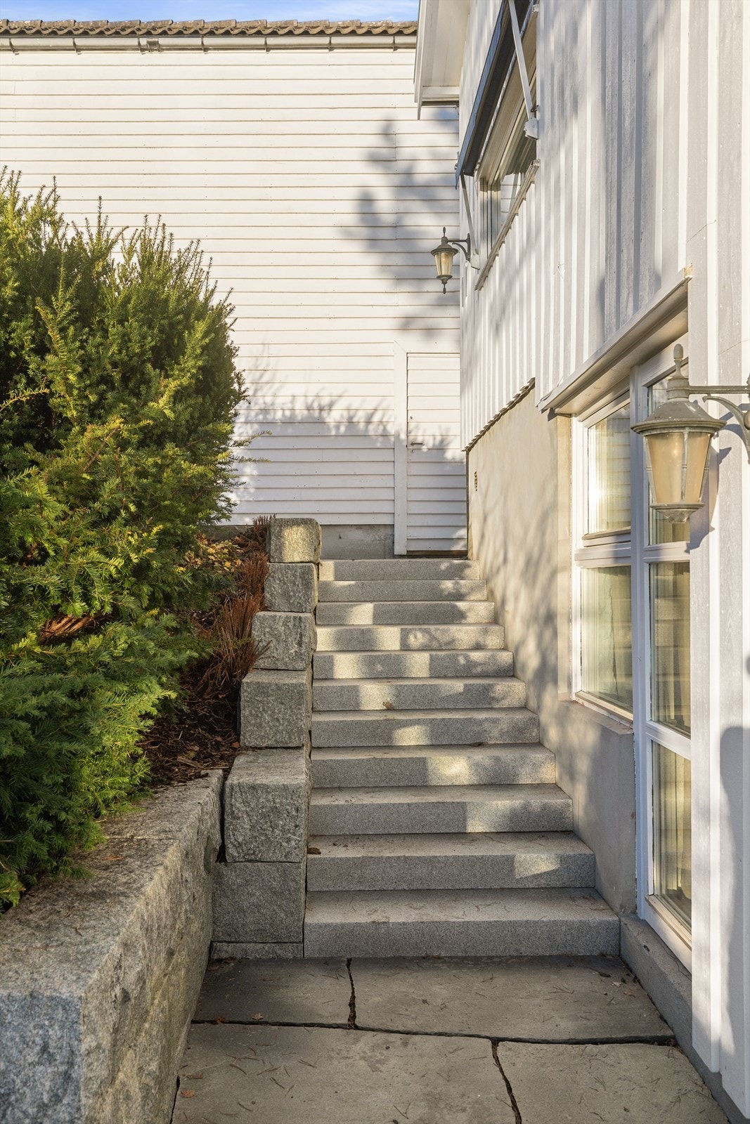 Tomt i flere plan opparbeidet med asfaltert innkjørsel, betong- og natursteinstrapper, samt støttemur i naturstein. I tillegg finnes plenarealer og variert beplantning. Galleribilde