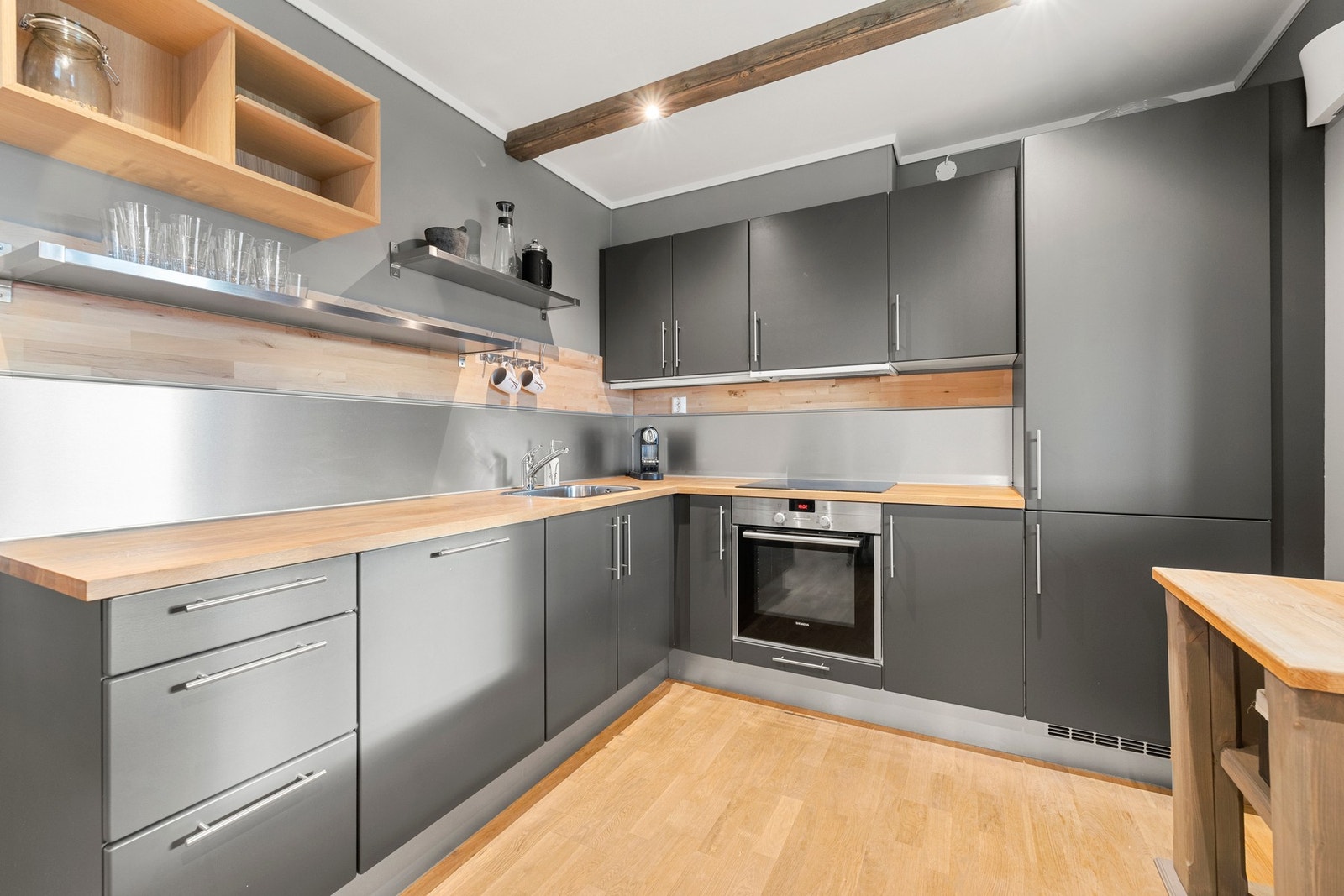 Kjøkkenet fremstår moderne og funksjonelt, med mørke fronter, heltre benkeplate og integrerte hvitevarer. Galleribilde