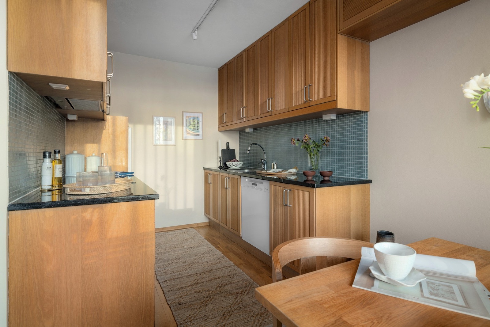 Innredningen med rillete fronter kombineres med benkeplate i granitt og nedfelt stålkum, mens mosaikkfliser over benkeplaten skaper en fin kontrast. Galleribilde