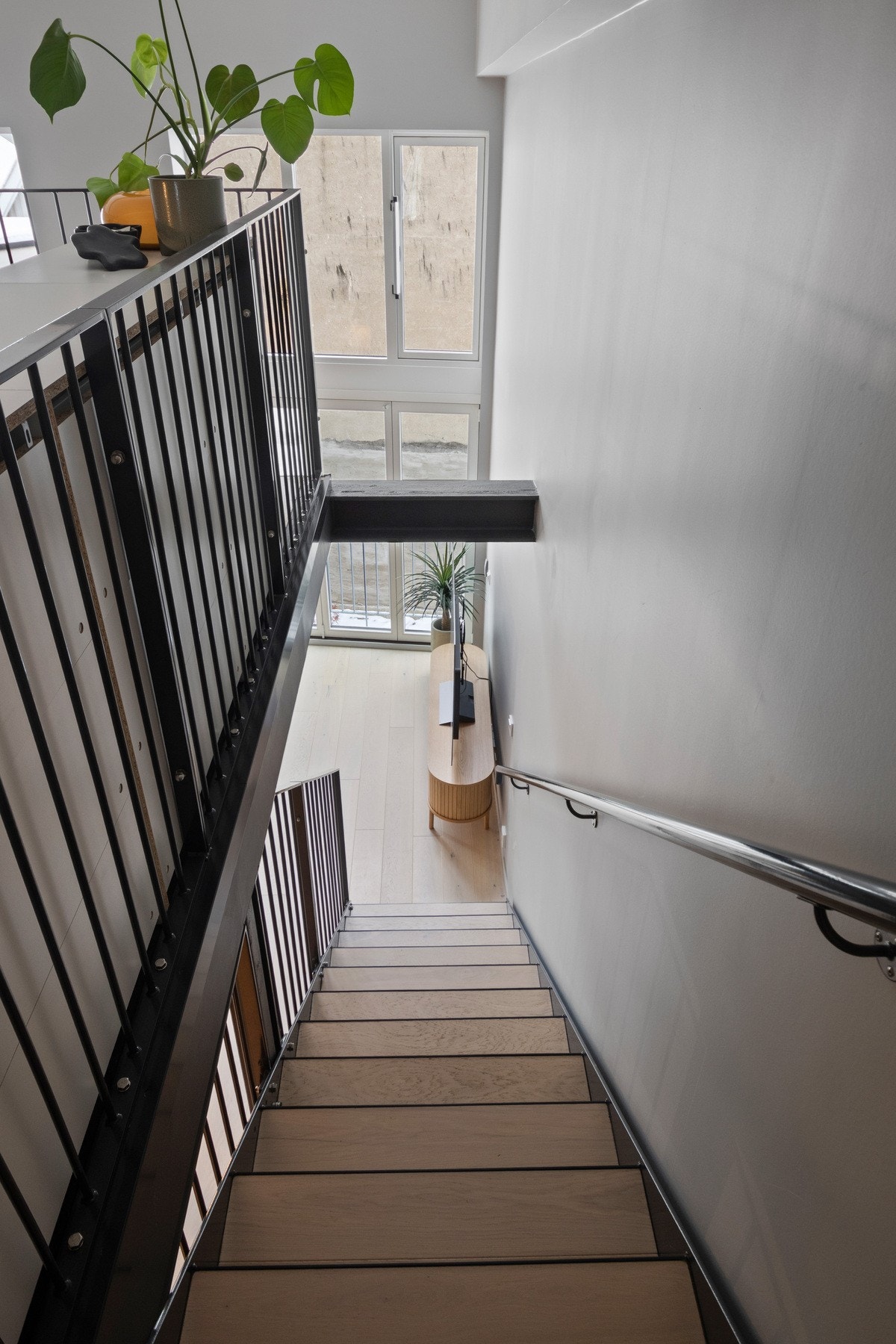 Fra allrommet som utgjør stue og kjøkken går det en sortlakkert ståltrapp opp til en romslig hems med soveplass. Galleribilde