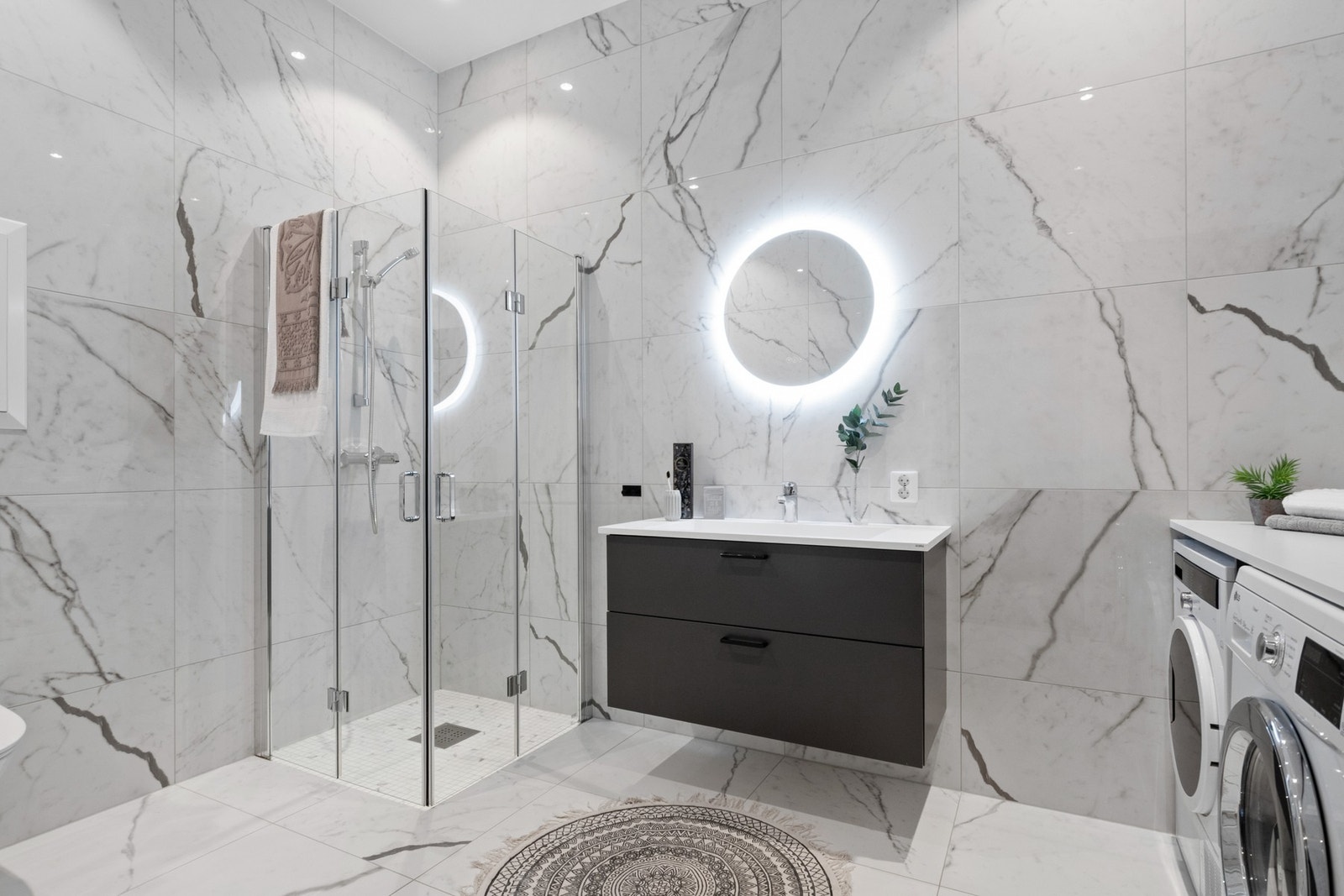 Leilighetens elegante baderom innbyr til egentid og velvære, med stilfulle materialvalg, flott takhøyde og moderne utstyr. Galleribilde