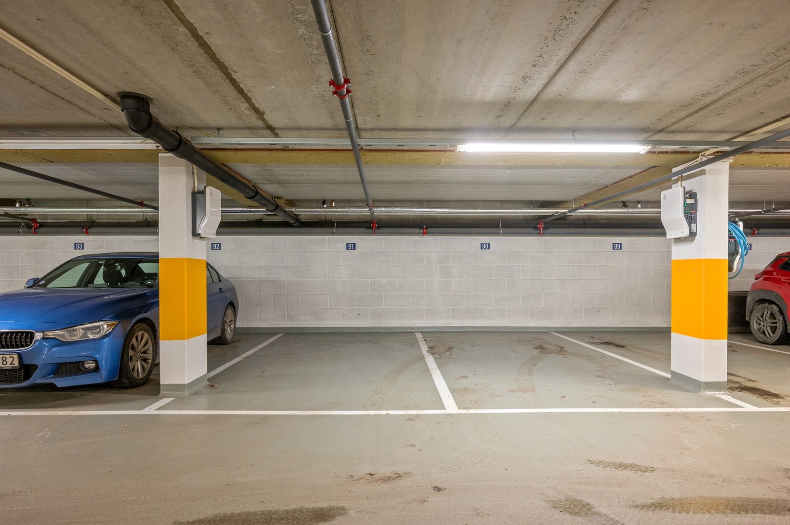 Romslige parkeringsplasser i nyere garasjeanlegg med el-bil lader. Galleribilde