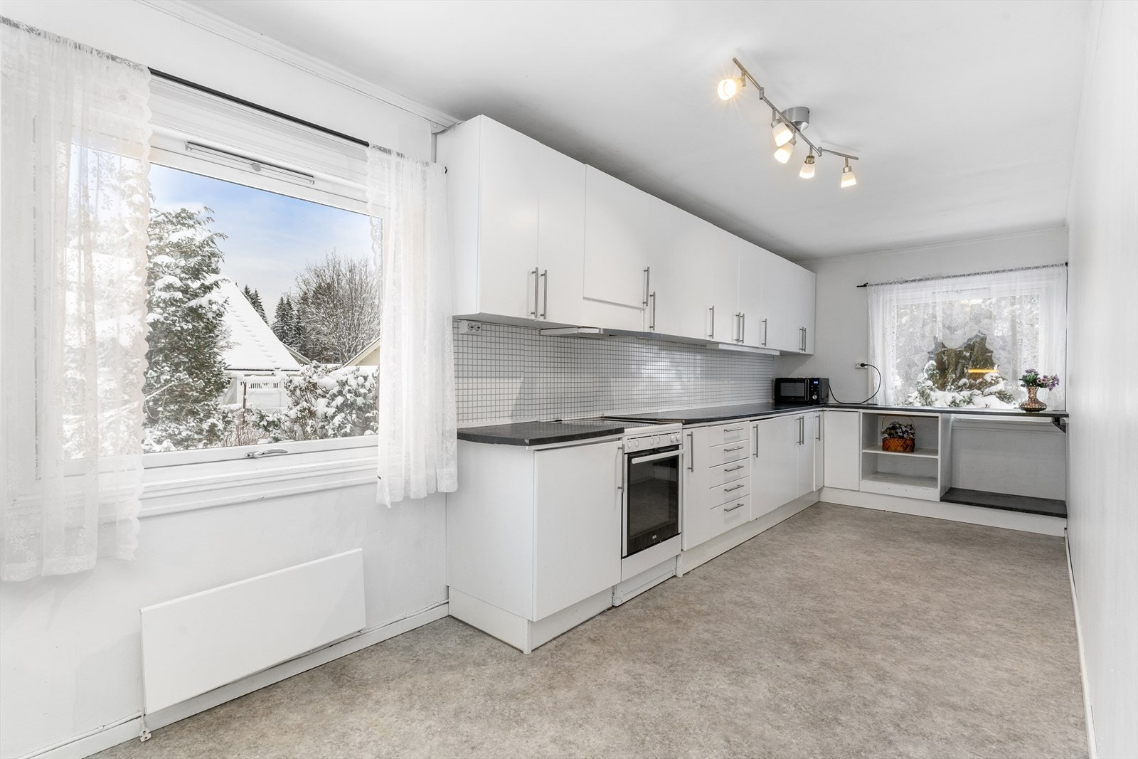 Klassisk, eldre kjøkkeninnredning med behandlet innredning med slette hvite og benkeplate av laminat. Galleribilde