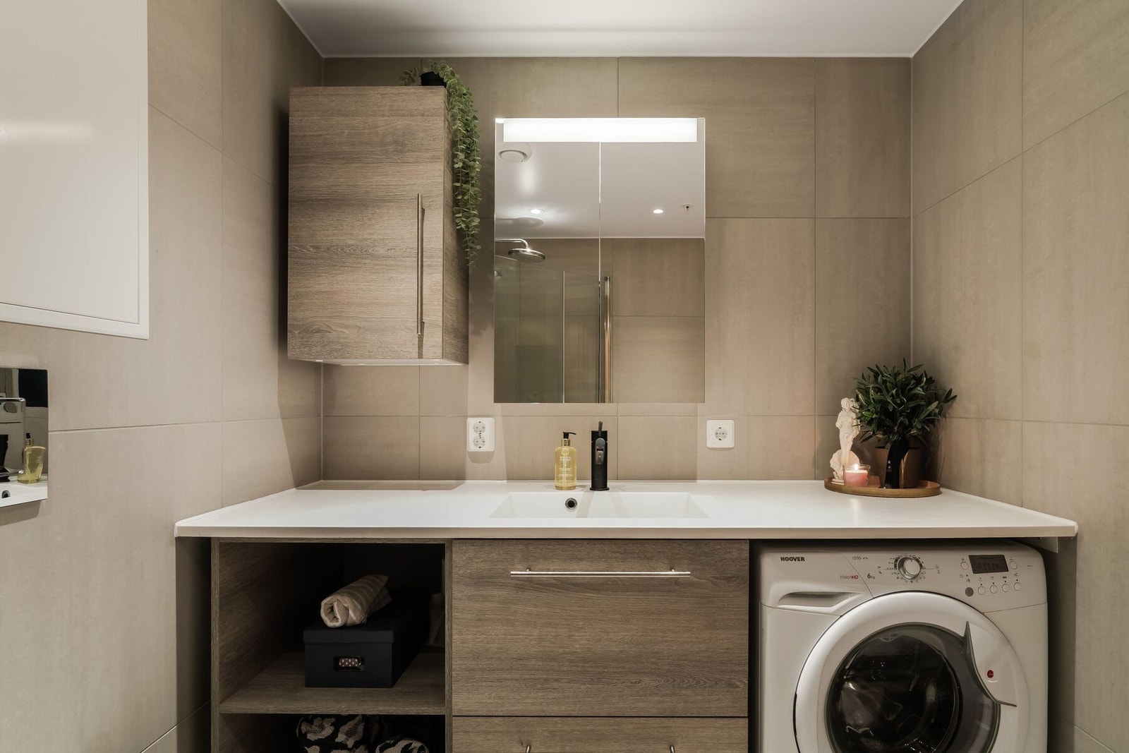 Badet fremstår som moderne, delikat og tidløst. Det er flislagt med beige fliser på både gulv og vegger, noe som gir en lun og behagelig spa-følelse. Helstøpt servant med underskap og egen plass for vaskemaskin. Galleribilde