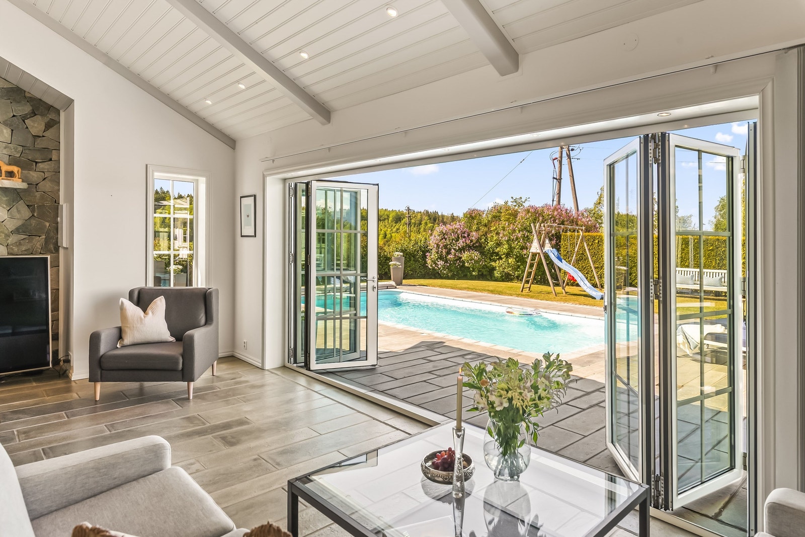 Fra stuen har man foldedører ut til en storslått uteområde med basseng. Galleribilde