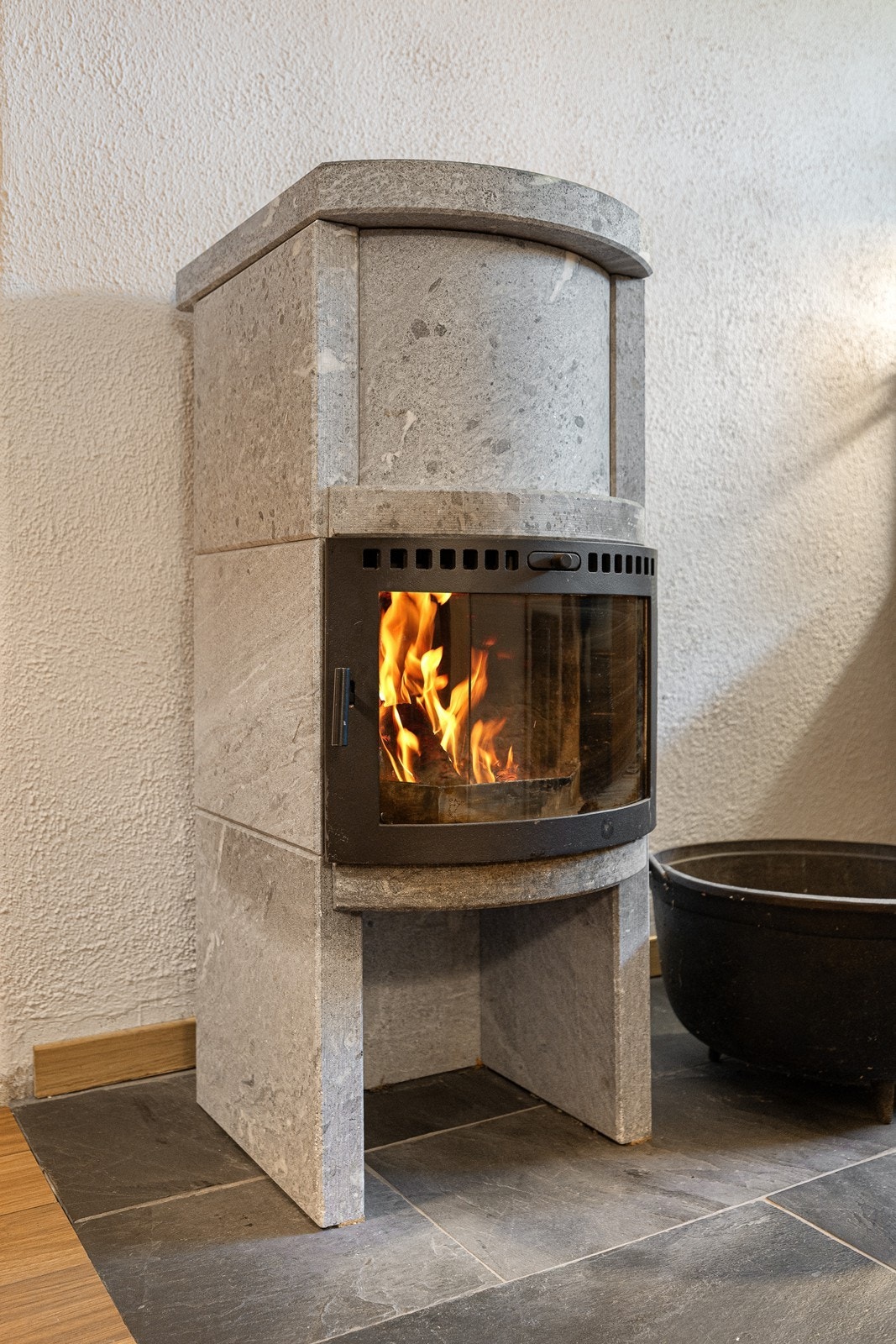 Sentralt i rommet er det en effektiv klebersteinsovn med innsats. Galleribilde