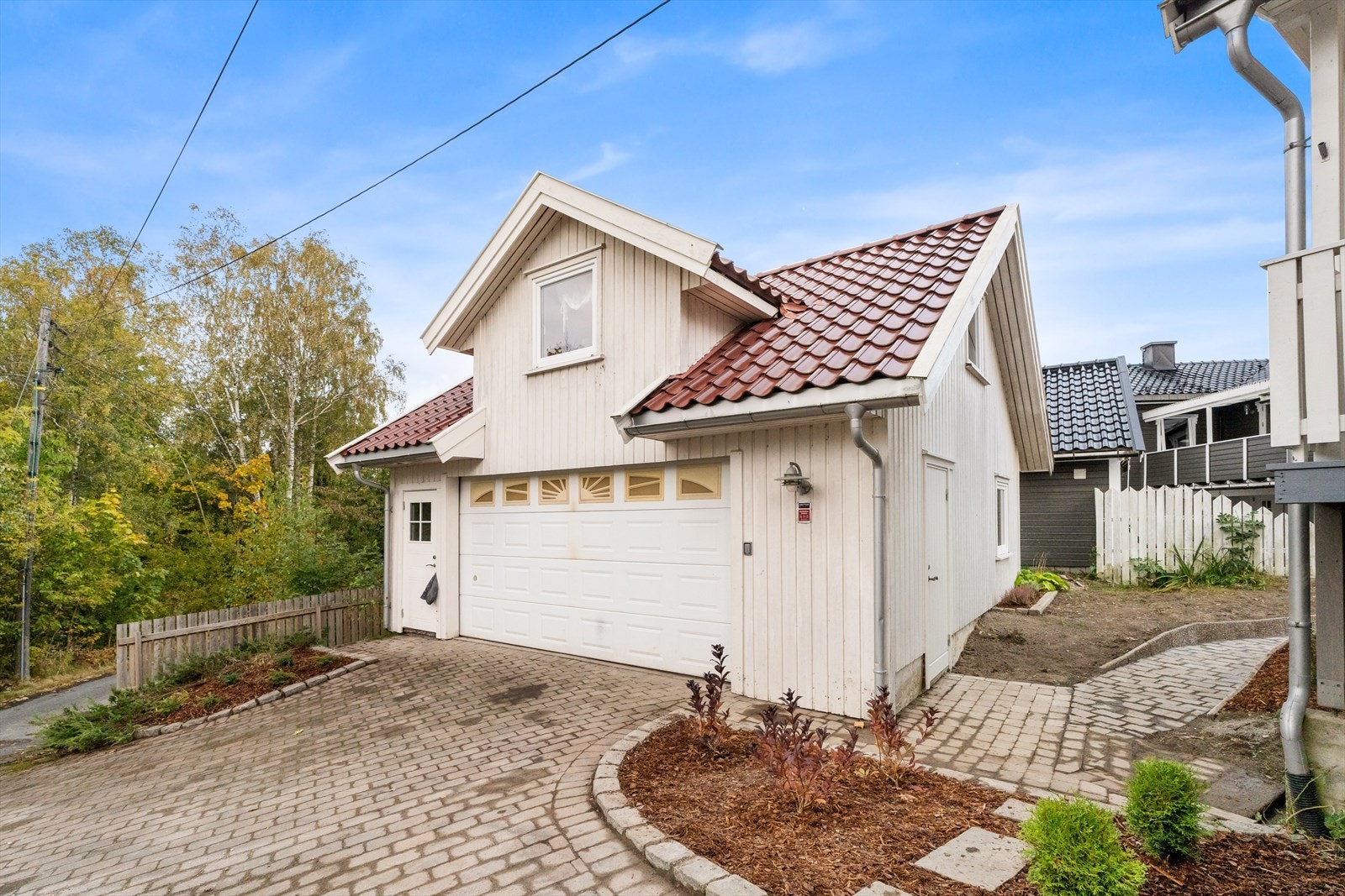 Frittstående garasje på ca. 46 m² med støpt dekke og elektrisk port.
Rommet over garasjen er innredet med stue/kjøkken og toalettrom. Denne er ikke godkjent for varig opphold, og rapporten fastslår at "vann og avløp ikke er godkjent innlagt i garasjen". Galleribilde