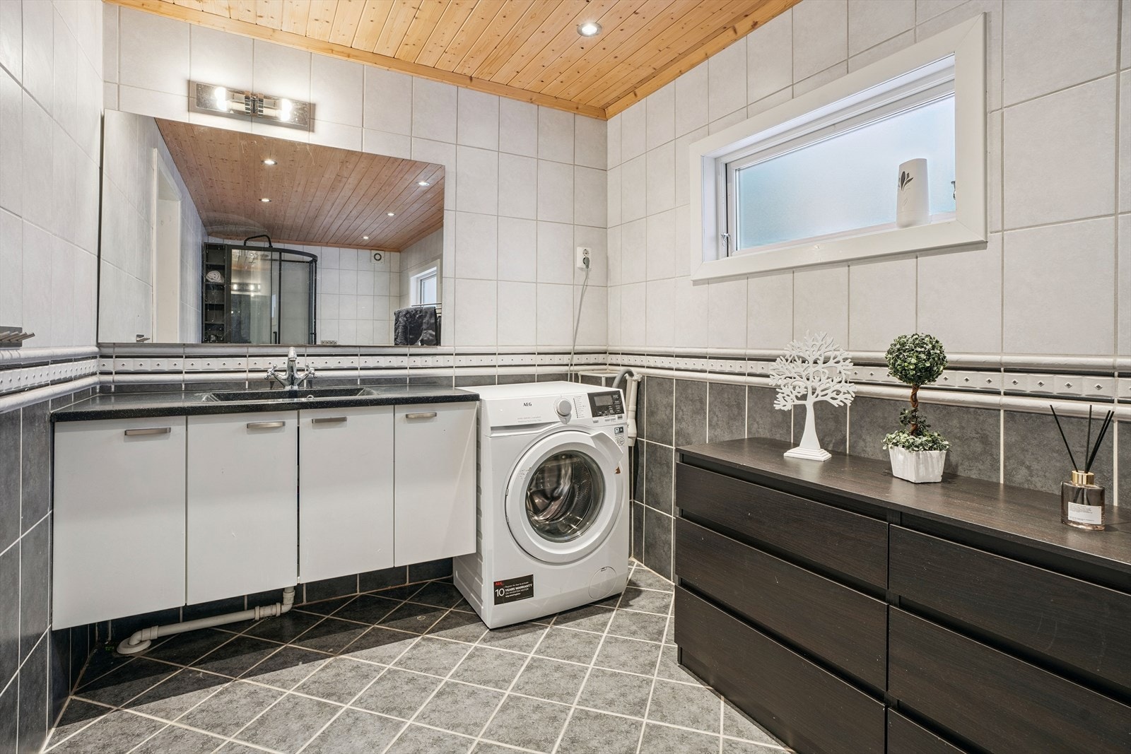 Rommet er kombinert vaskerom med opplegg for vaskemaskin og servantskap. Galleribilde