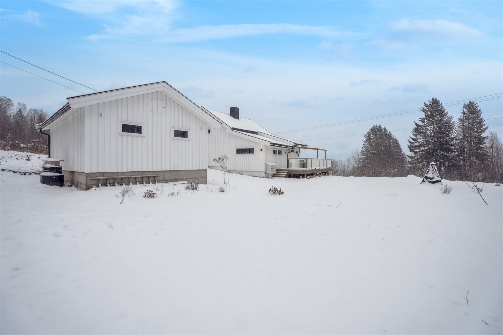 Eiendommen ligger i et svakt skrånet terreng med gruset gårdsplass og hage med plen. Galleribilde