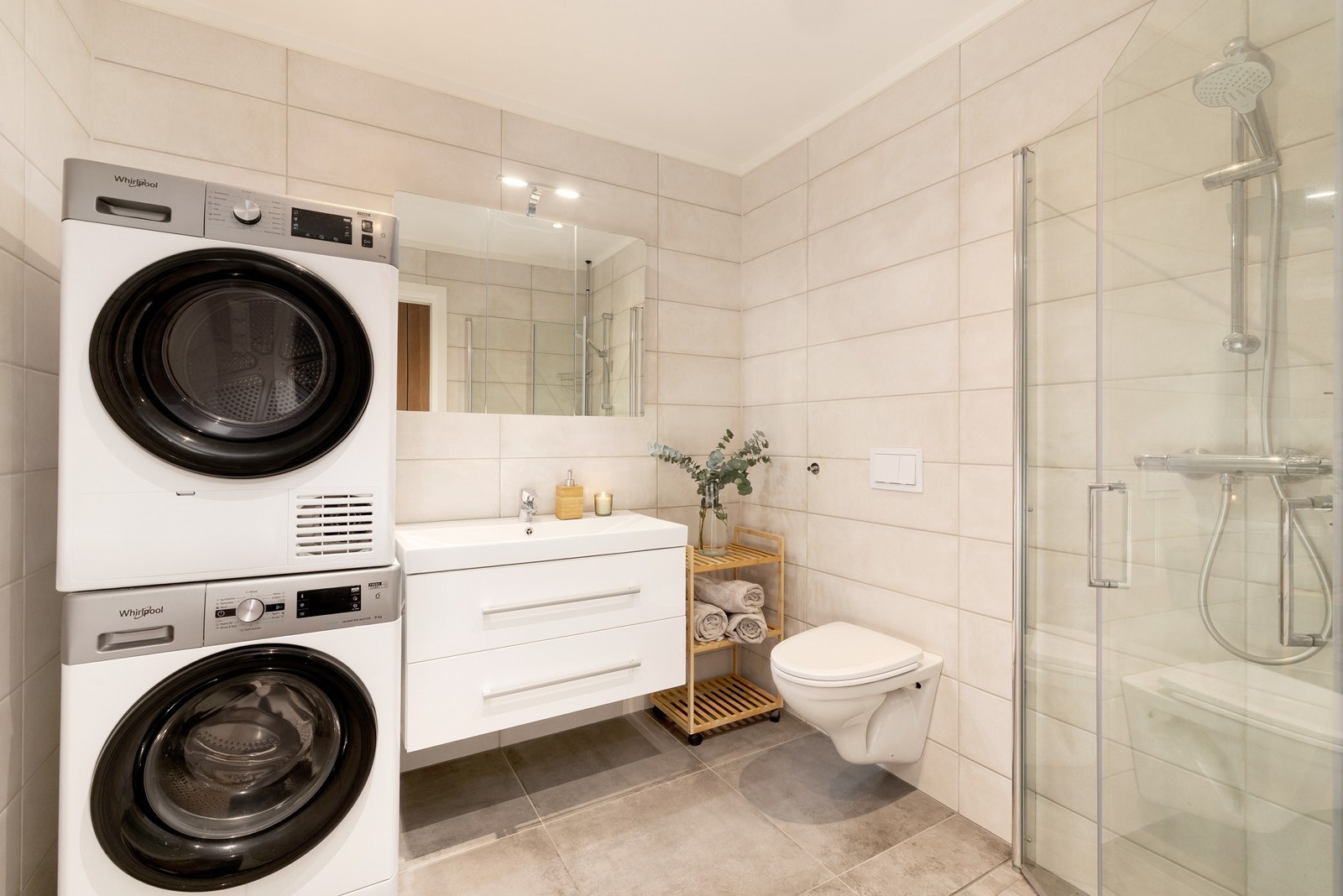 Delikat flislagt bad med varme i gulv. Inneholder dusjhjørne, servant, vegghengt wc og opplegg for vaskemaskin. Galleribilde