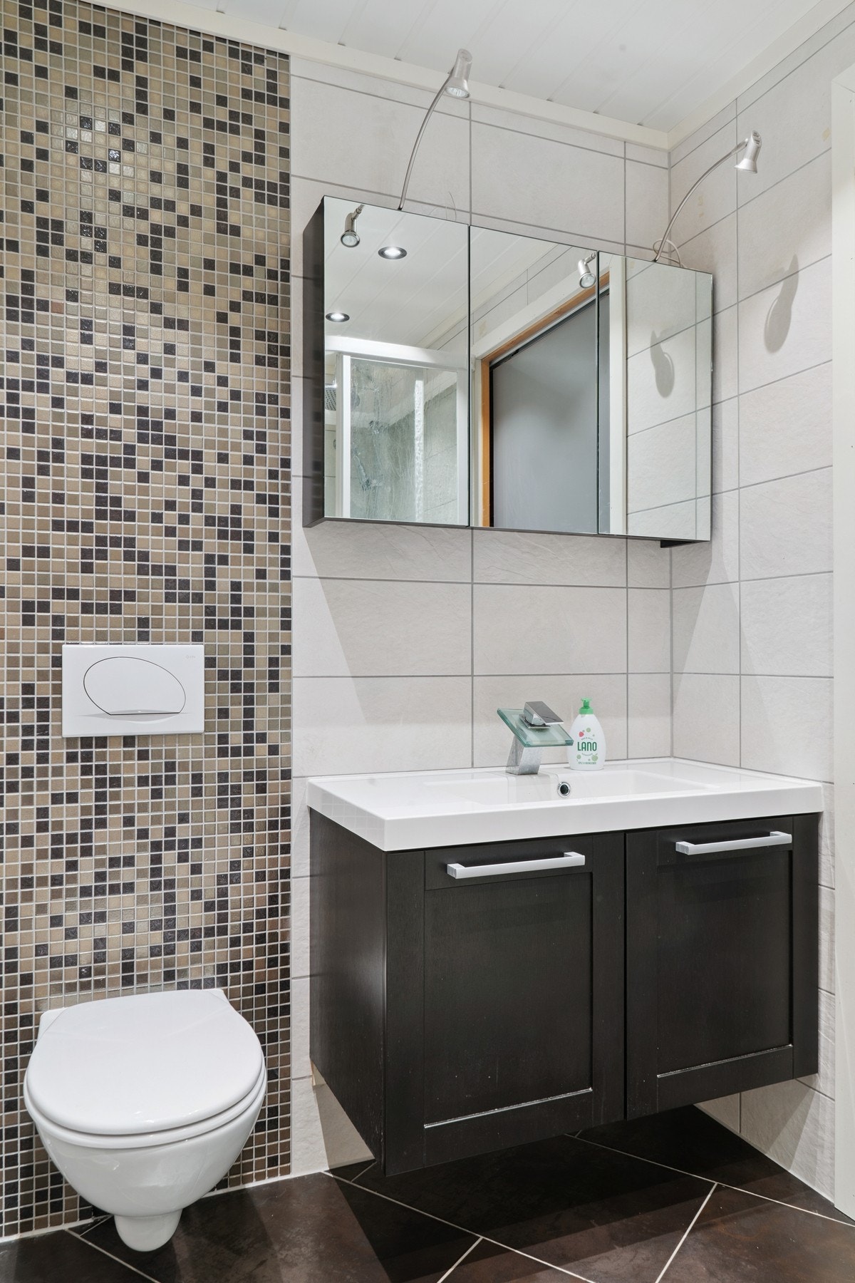 Rommet har innredning med nedfelt servant, speilskap med
belysning, veggmontert toalett med innebygget sisterne og
dusjkabinett Galleribilde