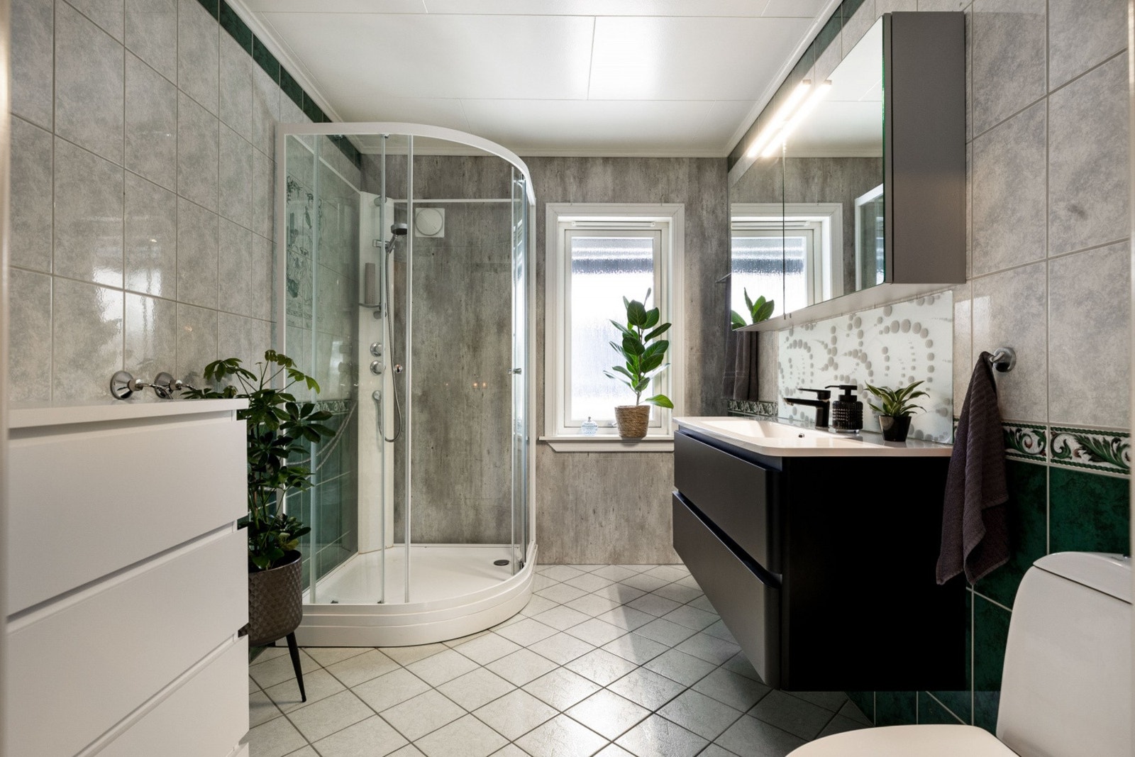 Badet har dusjkabinett, servant med speilskap, og et vindu som gir naturlig lys. Galleribilde