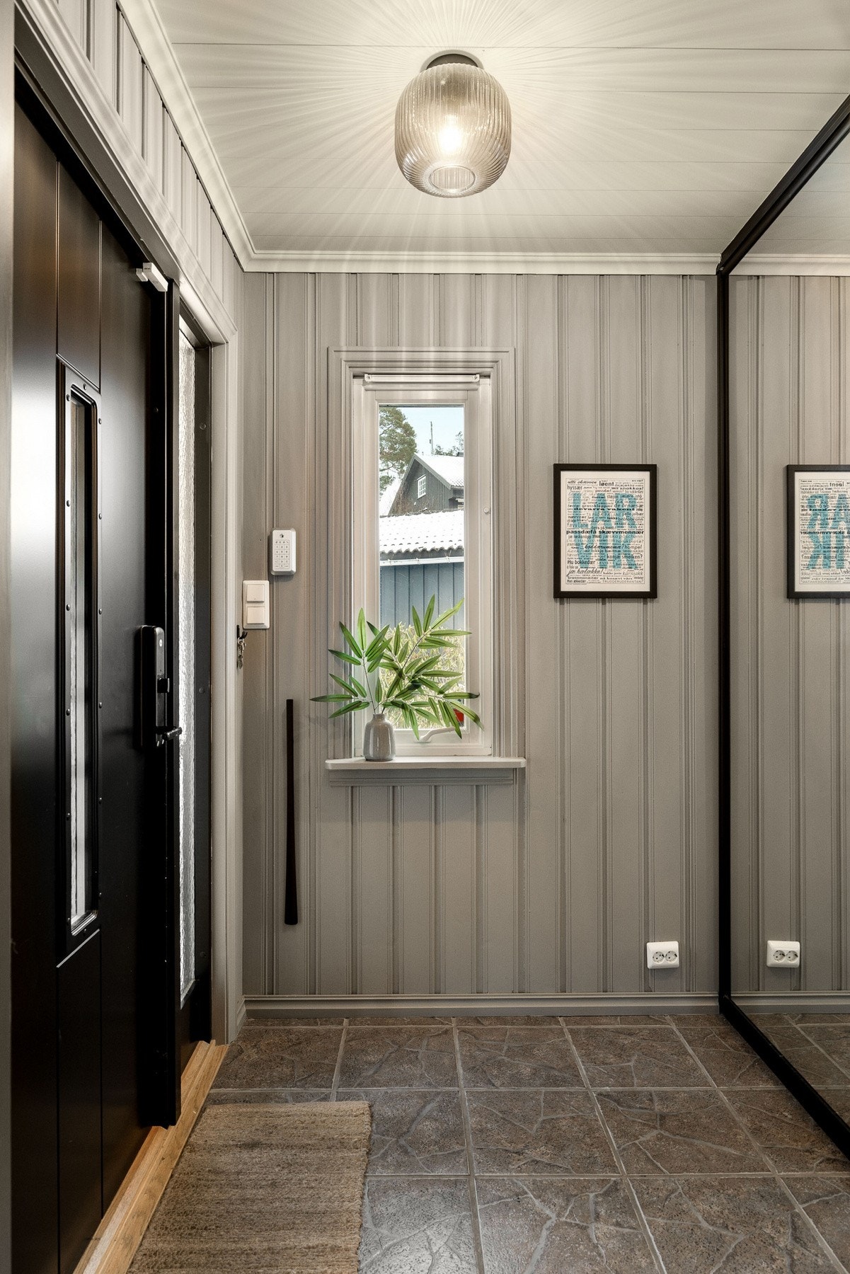 Entré med grå panelvegger, flislagt gulv, vindu og speilskap for oppbevaring. Galleribilde