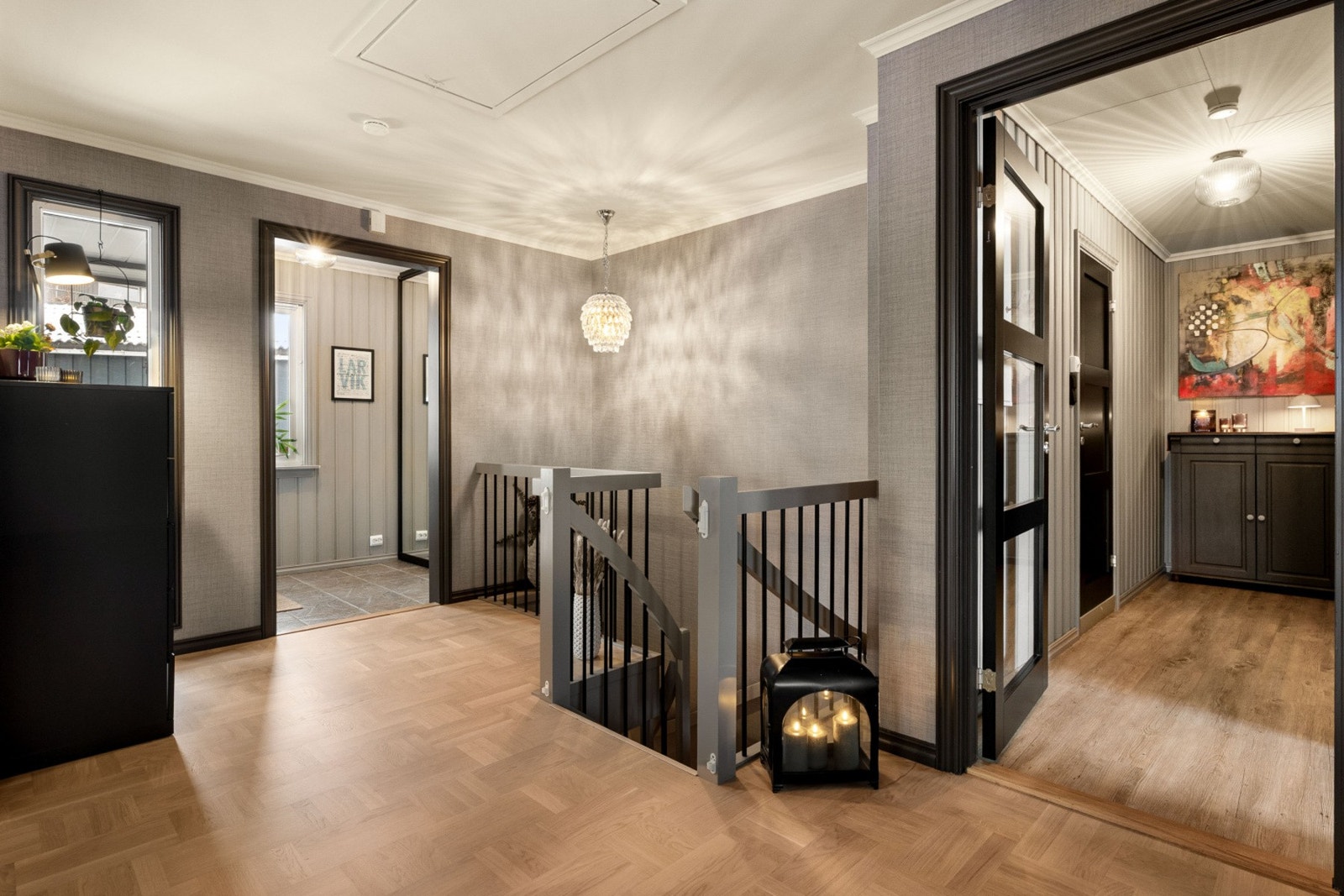 Lyst og moderne gangområde med parkettgulv og trappeadkomst. Veggene har en nøytral farge som gir et elegant preg. Galleribilde