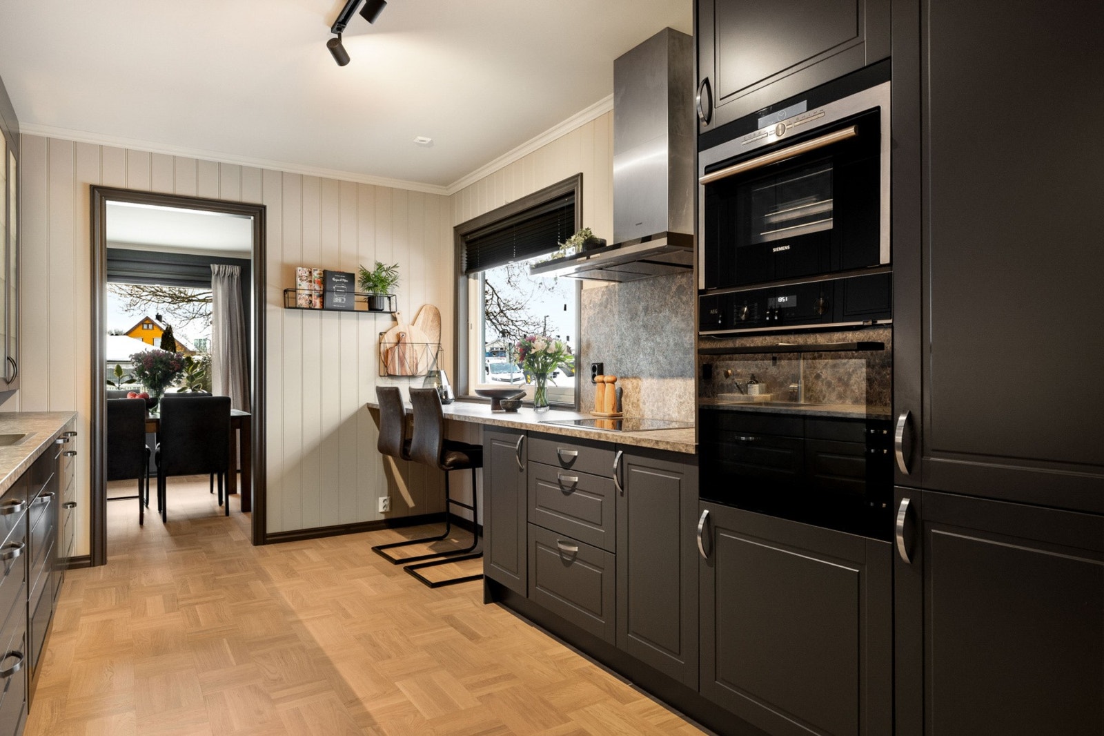 Moderne kjøkken med integrerte hvitevarer og spiseplass ved vinduet. Galleribilde