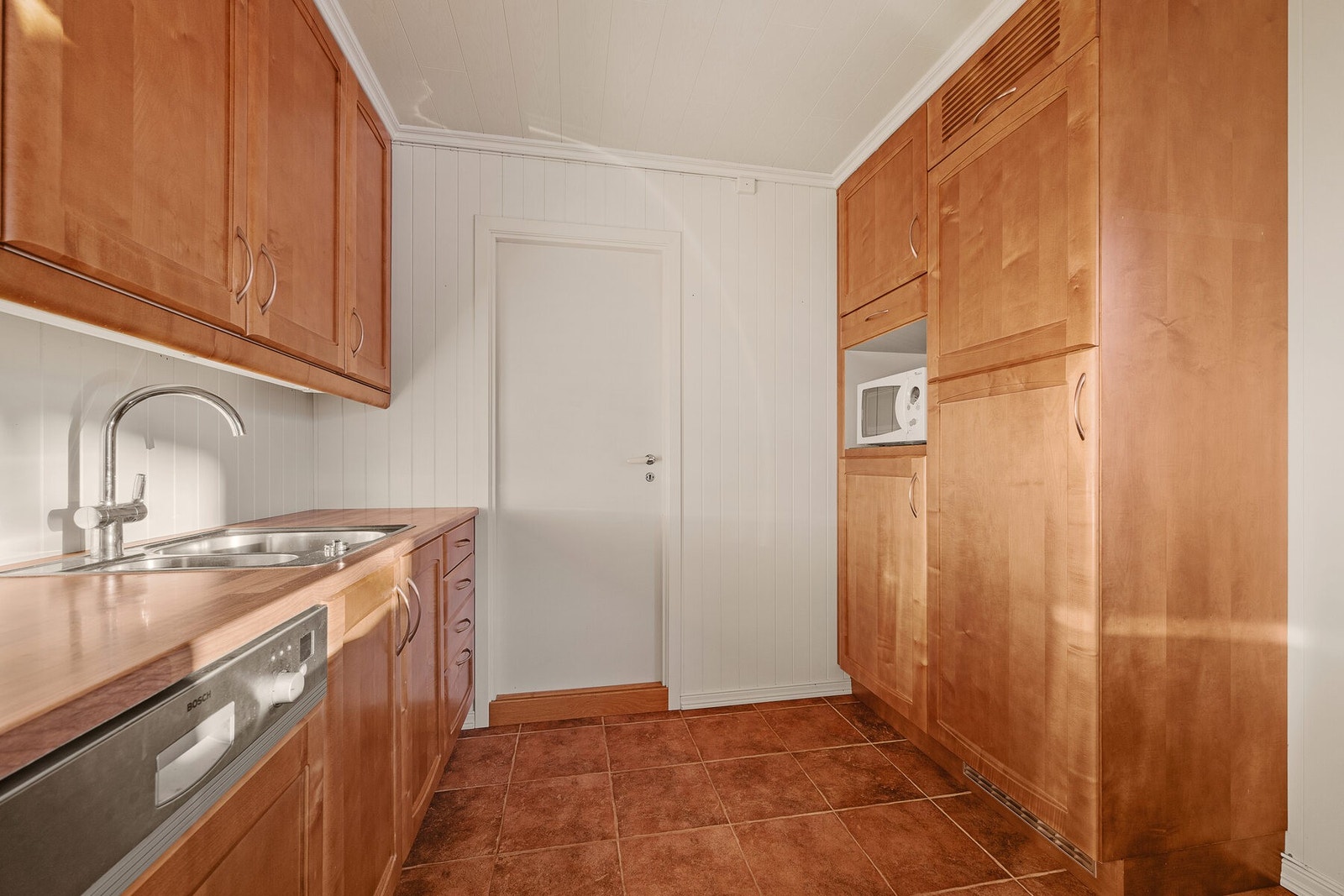 Kjøkkenet har godt med skap- og benkeplass. Døren fører til vaskerommet, gang med egen utgang, samt kjelleretasjen. Galleribilde