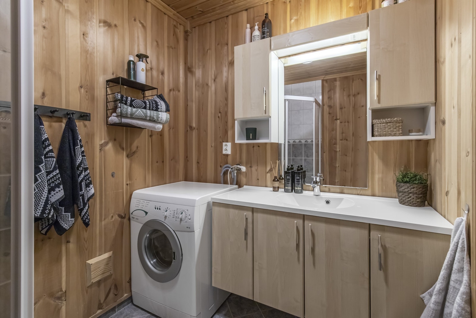 Bad i hovedetasjen er innredet med dusjhjørne, servant i innredning, toalett og opplegg til vaskemaskin Galleribilde