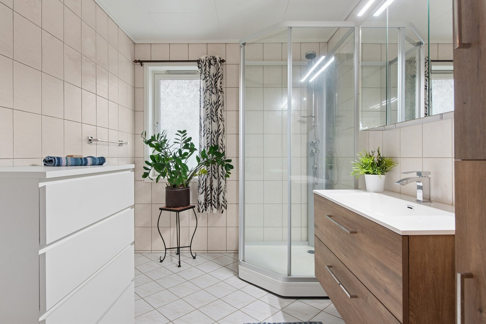 Badet er innredet med baderomsinnredning med servant og et dusjkabinett. Galleribilde