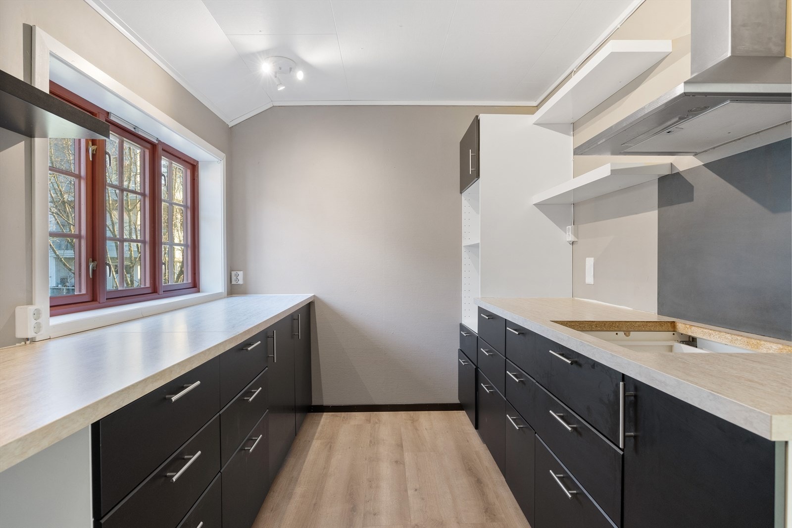 Kjøkkenet er praktisk innredet med glatte, malte fronter og laminat benkeplate, og er tilrettelagt for oppvaskmaskin, platetopp og stekeovn. Galleribilde