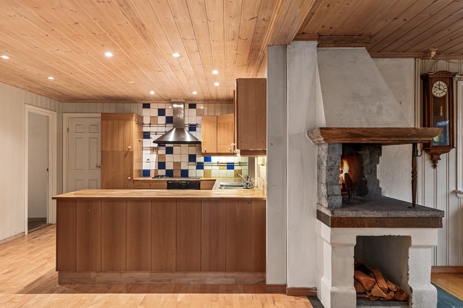 Peisen mellom spisestuen og kjøkkenet skaper en naturlig og hyggelig romdeler. Galleribilde