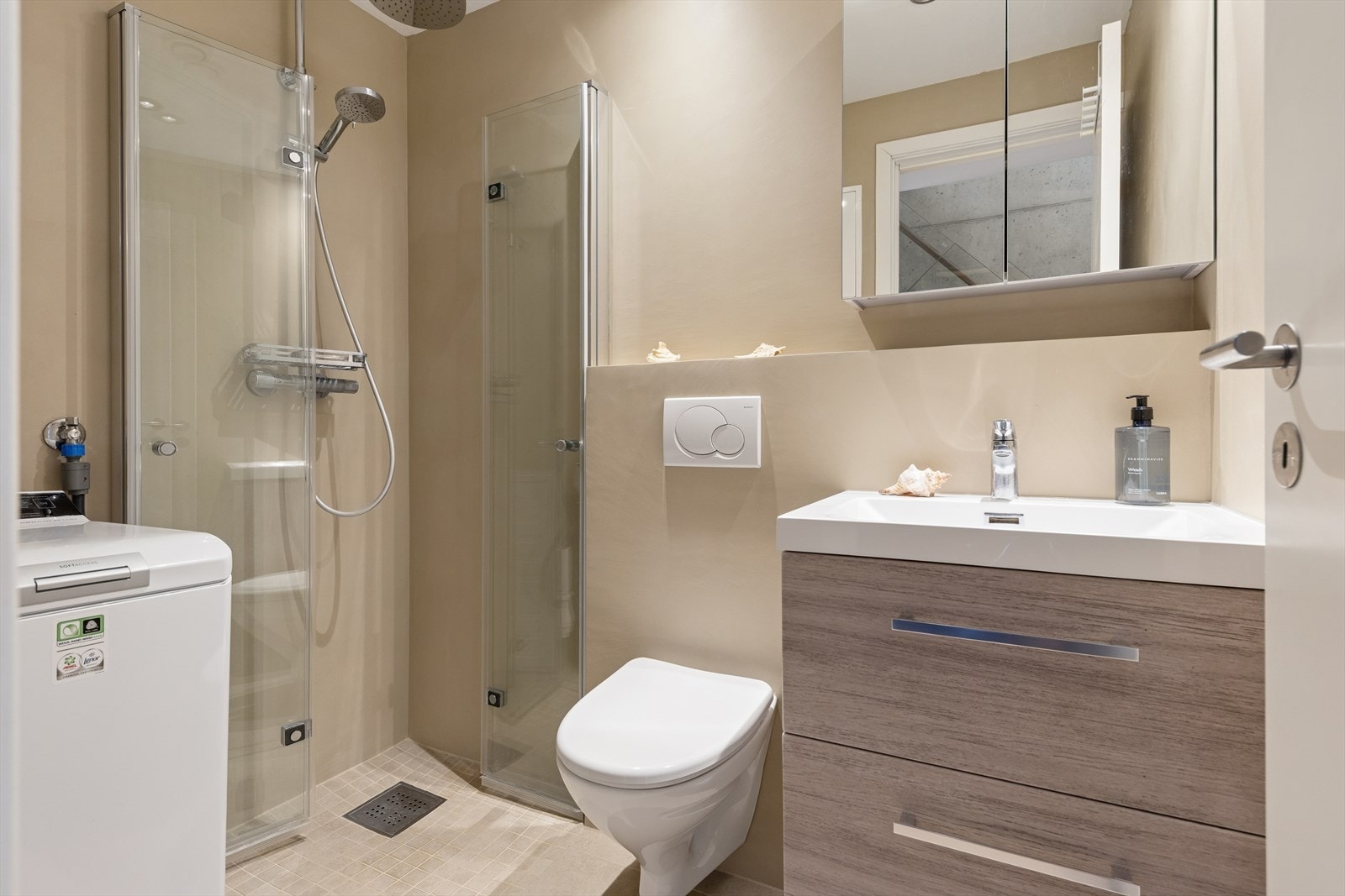 Baderom i leiligheten er innredet med servant med innredning, dusj, vegghengt toalett og opplegg for vaskemaskin. Badet er overflateoppusset i 2025. Galleribilde