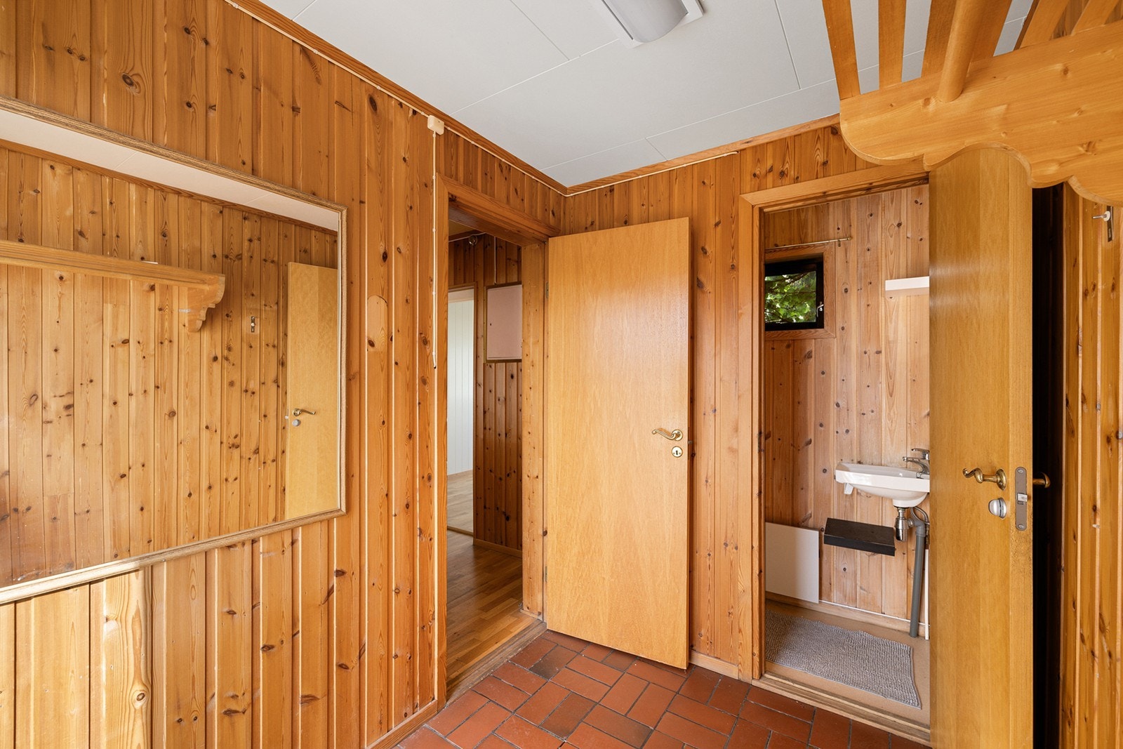 Romslig gang med panelte vegger i heltre furu og flislagt gulv ved inngangspartiet. Her er det også adkomst til gjestetoalett samt videre inn til boligens oppholdsrom. Galleribilde