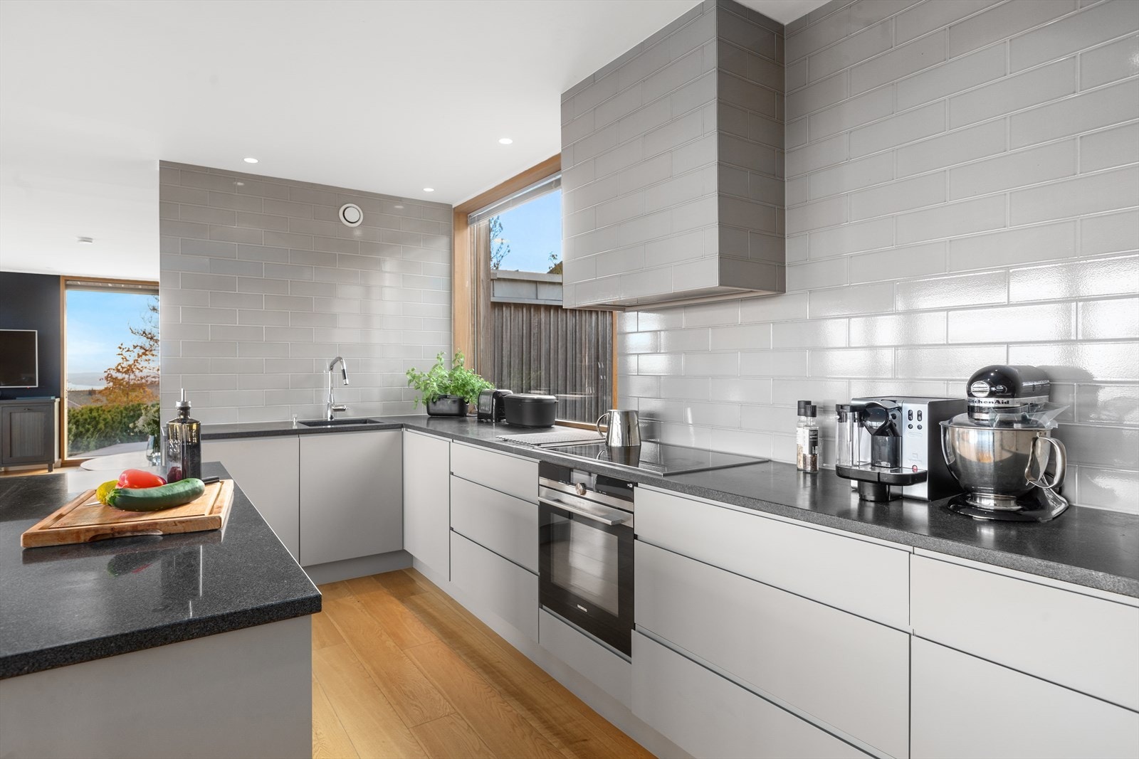 Bred induksjonstopp og kombiovn med fliser over benk. Galleribilde