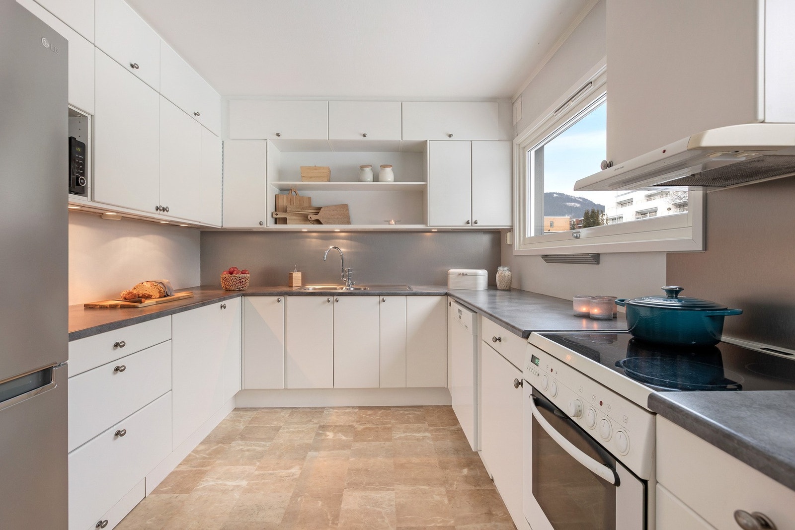 Lyst og moderne kjøkken med god benkeplass, frittstående hvitevarer og 2 vinduer som gir naturlig lysinnfall. Galleribilde