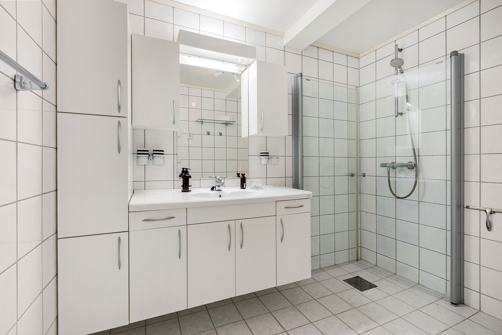 Lyst bad med dusjhjørne, dobbeltvask og godt med skapplass. Flislagte vegger og gulv. Galleribilde