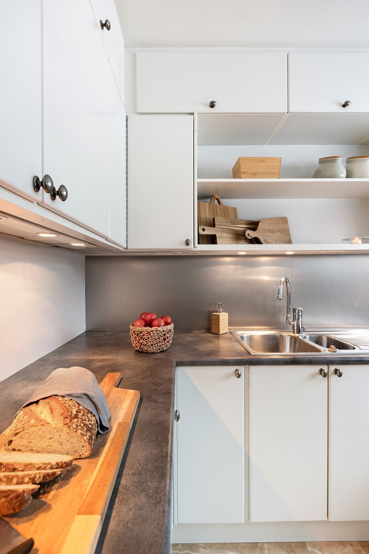 Moderne kjøkken med lyse skap, dobbel vask og god benkeplass. Praktiske hyller for oppbevaring over vasken. Galleribilde