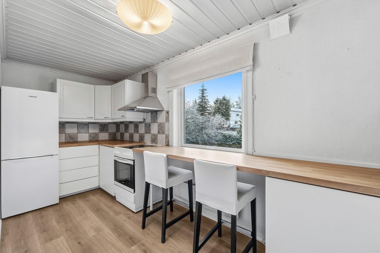 Separat kjøkken oppgradert med nye underskap og benkeplate i 2021. Innredningen har profilerte hvitmalte overskap kombinert med slette underskap, fliser mellom over- og underskap, og integrert belysning. Galleribilde