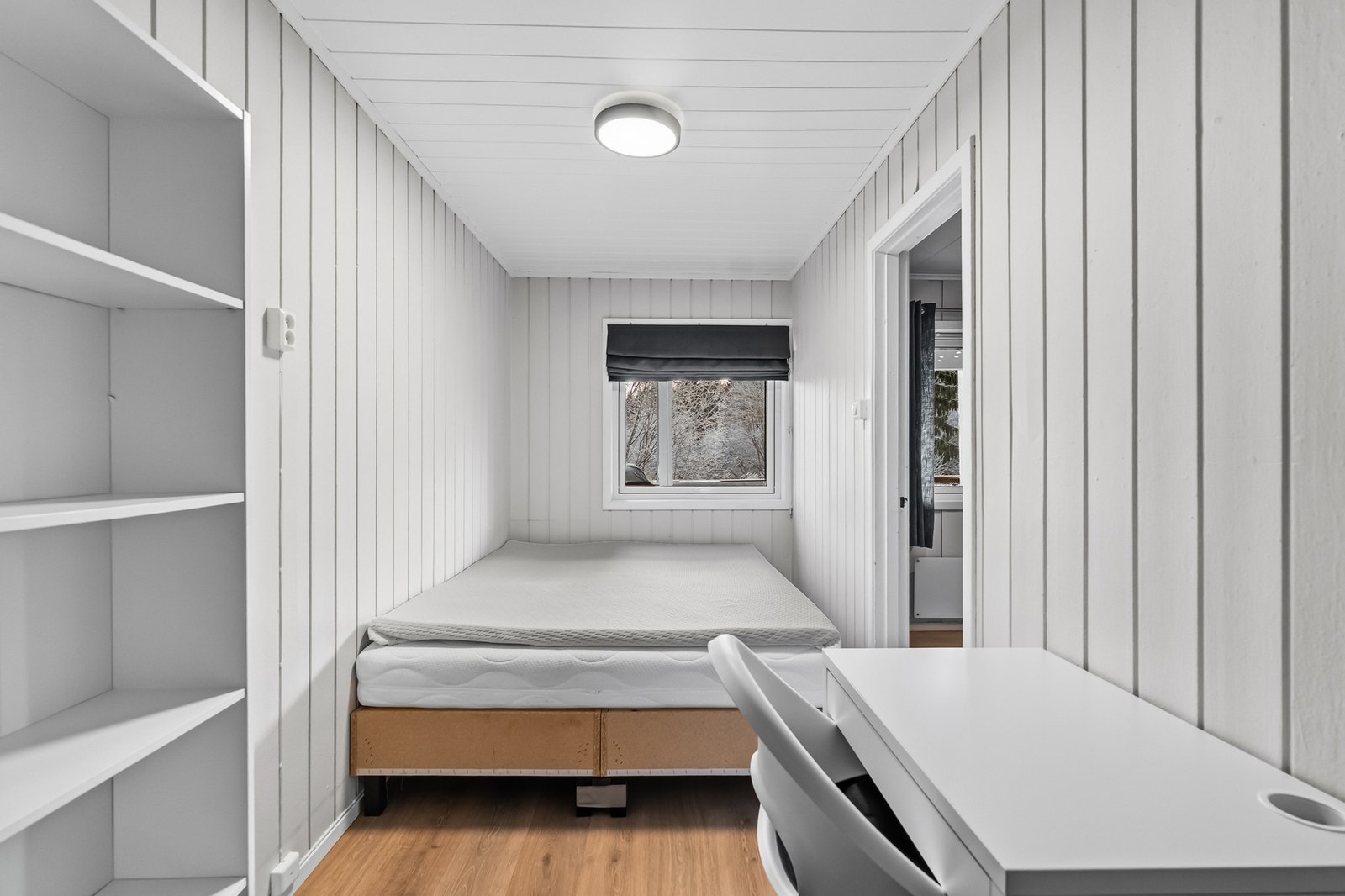 Leiligheten har et romslig soverom innenfor stuen. Rommet har lysmalt panel på veggflater, laminat på gulv og et stort vindu som slipper inn rikelig med lys. Galleribilde