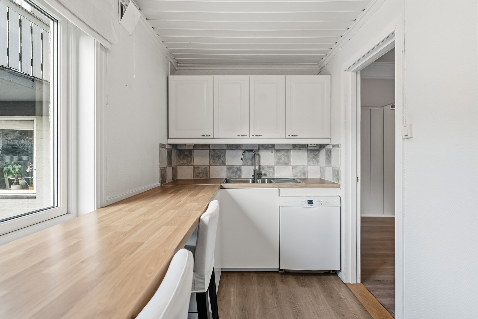 Frittstående hvitevarer medfølger: komfyr, oppvaskmaskin og kombinert kjøle-/fryseskap. Elektrisk ventilator er montert over kokesonen. Koselig spiseplass er etablert under vinduet med forlenget benkeplate. Galleribilde