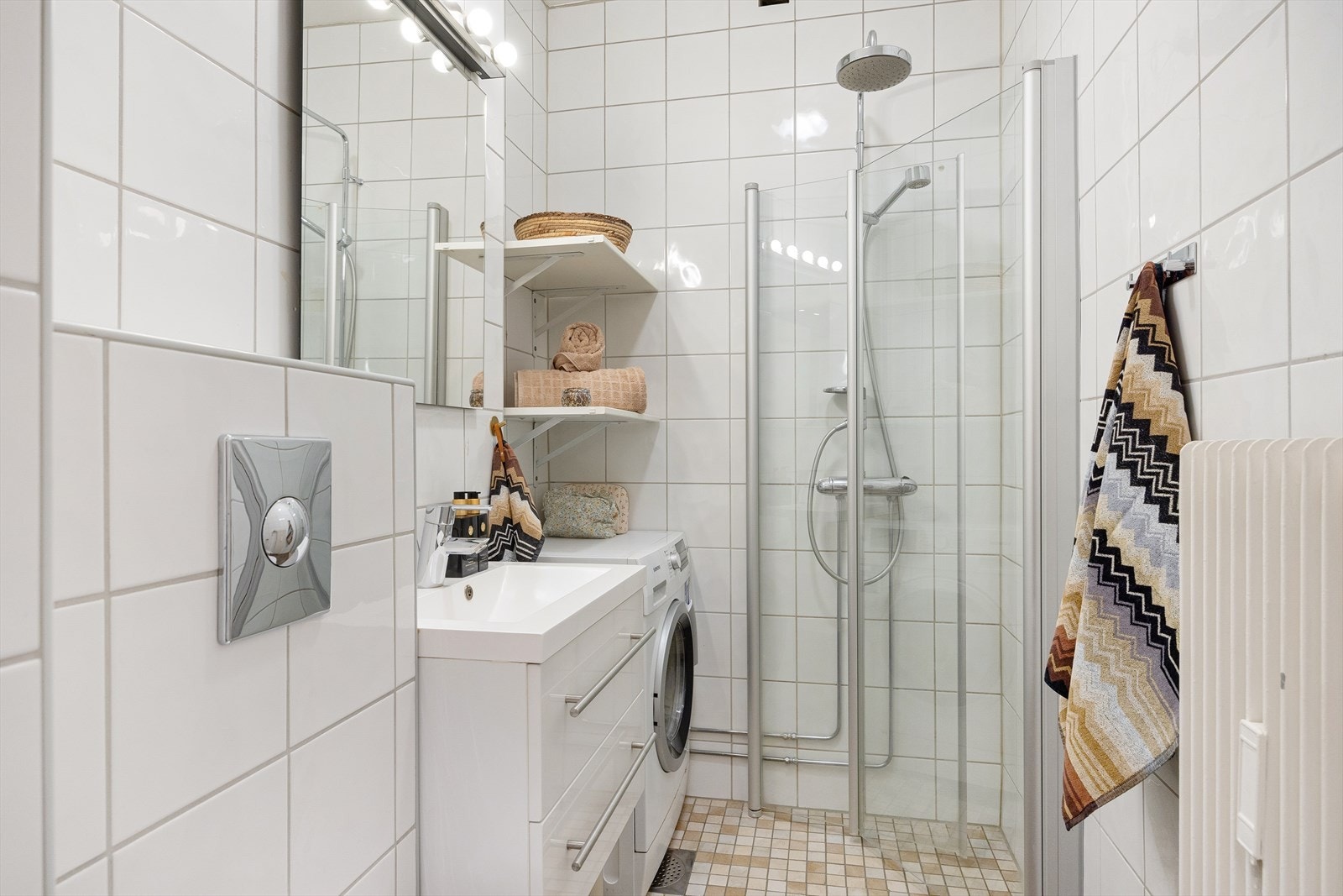 Badet er innredet med vegghengt klosett, servant nedfelt i innredning, speil og dusjhjørne med mosaikkfliser. Det er naturlig avtrekksventilasjon og opplegg for vaskemaskin. Galleribilde