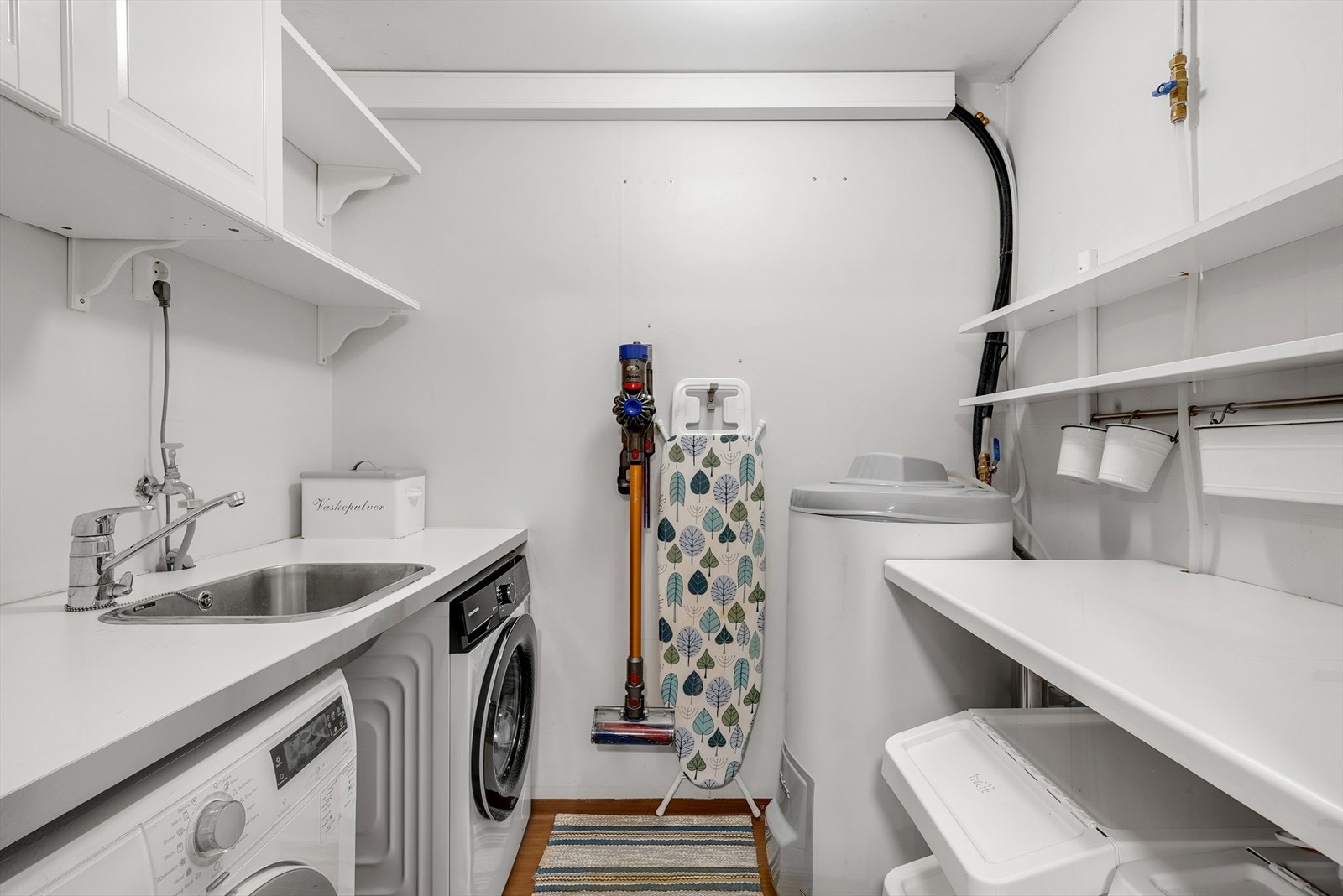 Praktisk vaskerom med skap, benkeskap og opplegg for vaskemaskin. Galleribilde